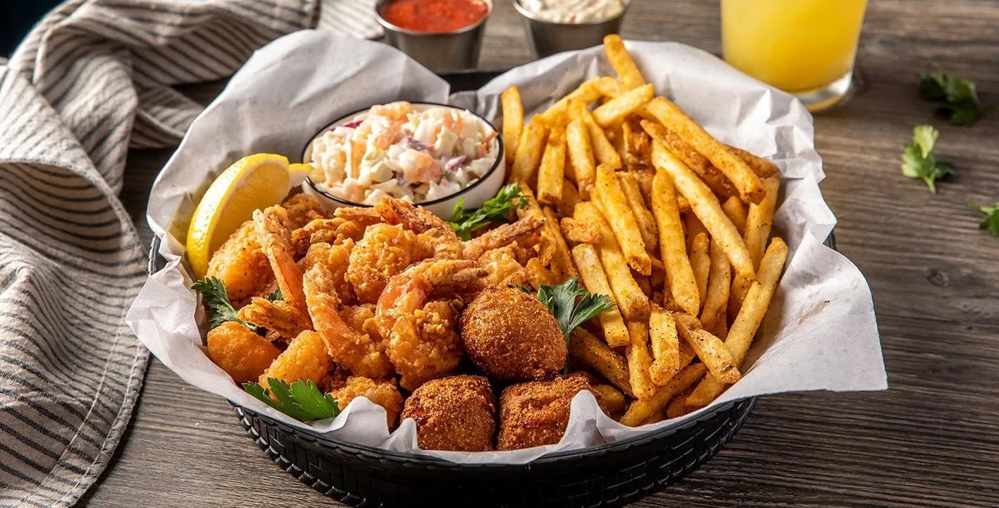 Fried shrimp, coleslaw, and fries served in a basket with lemon.