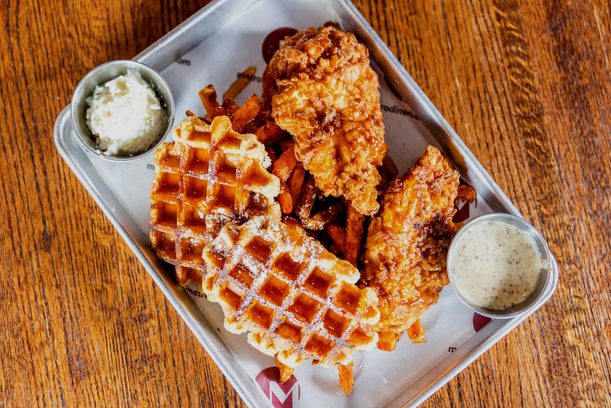 Delicious chicken and waffles served with syrup and garnish.