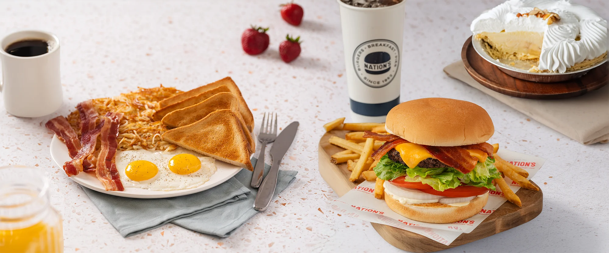 Breakfast plate with eggs, bacon, toast, and a burger with fries.