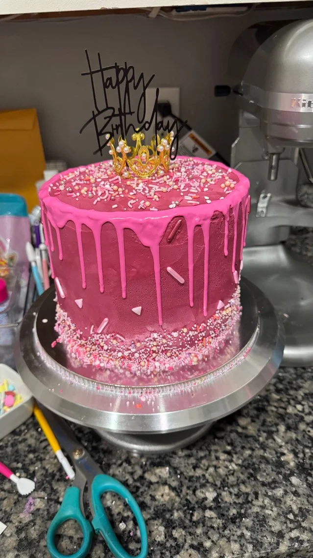Colorful birthday cake with pink frosting and crown decoration