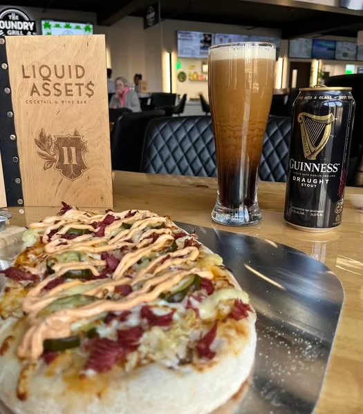 Reuben pizza with craft beer in a modern bar setting
