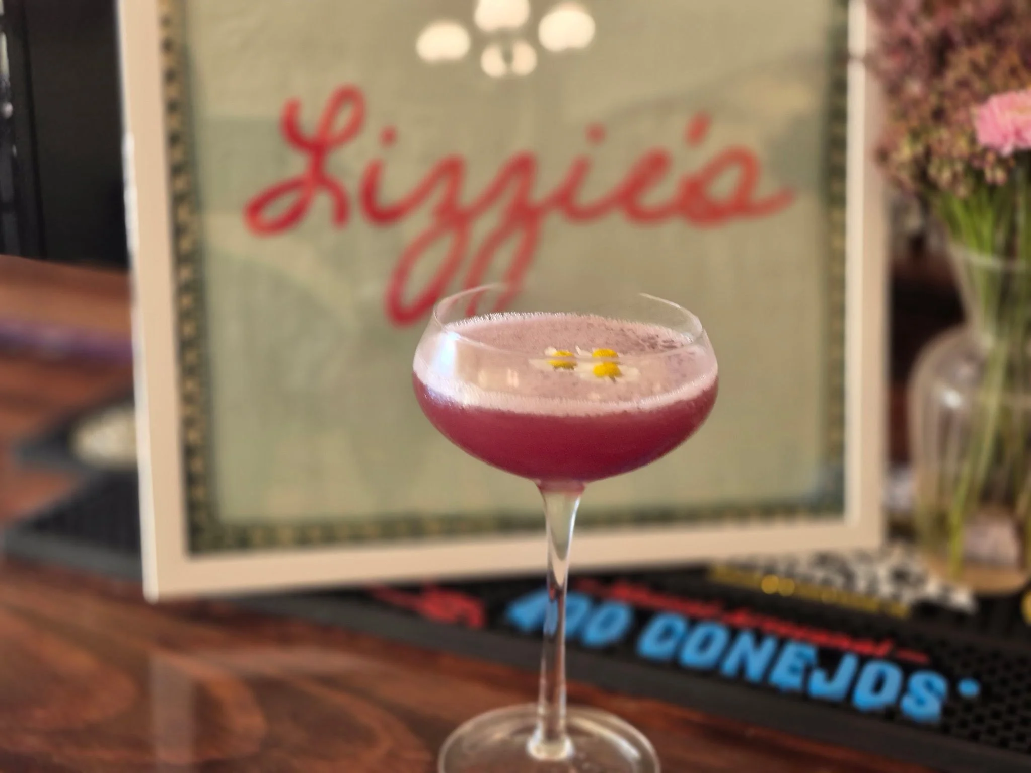 Craft cocktail with floral garnish at a vibrant bar