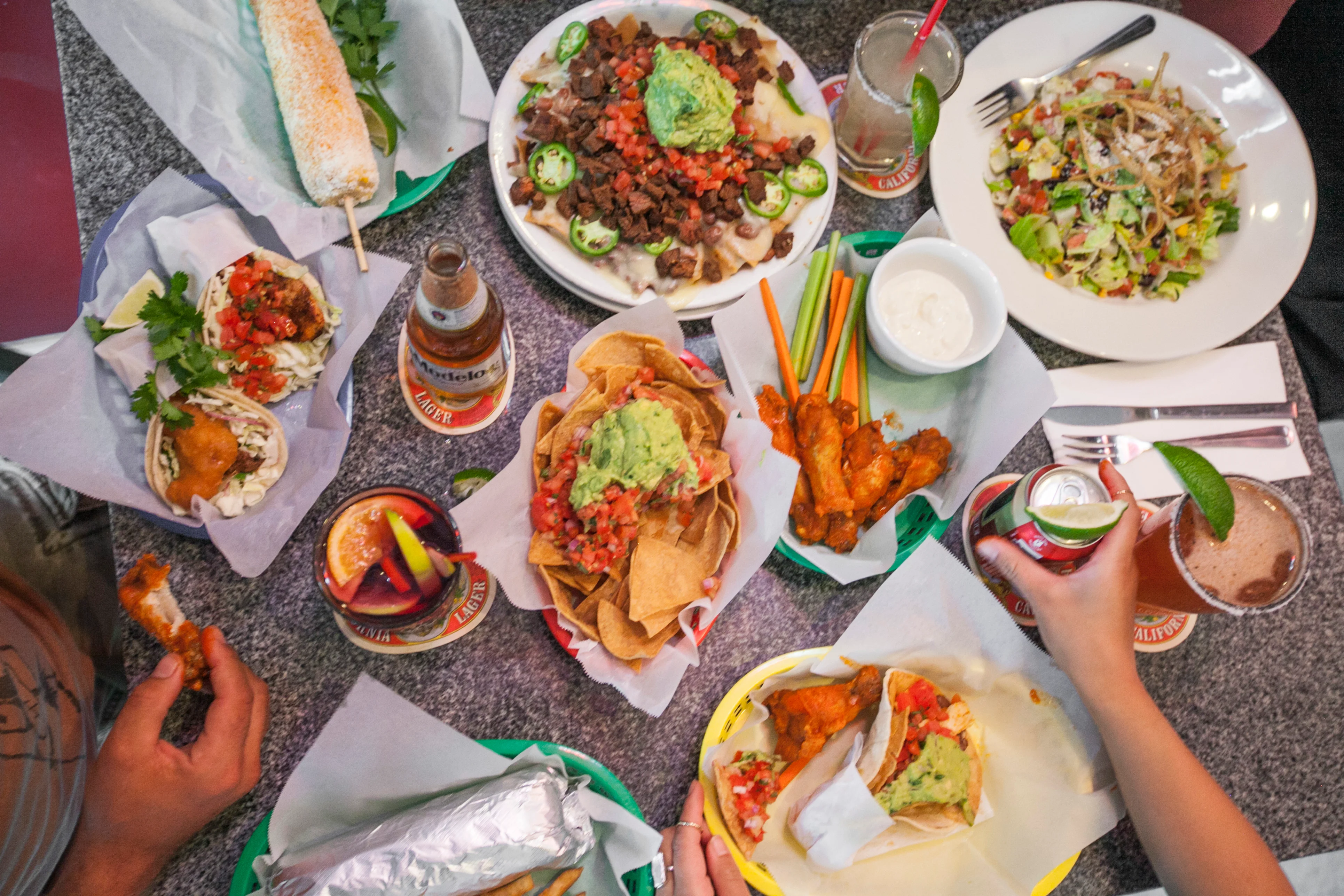 Colorful Mexican feast with tacos, nachos, and drinks