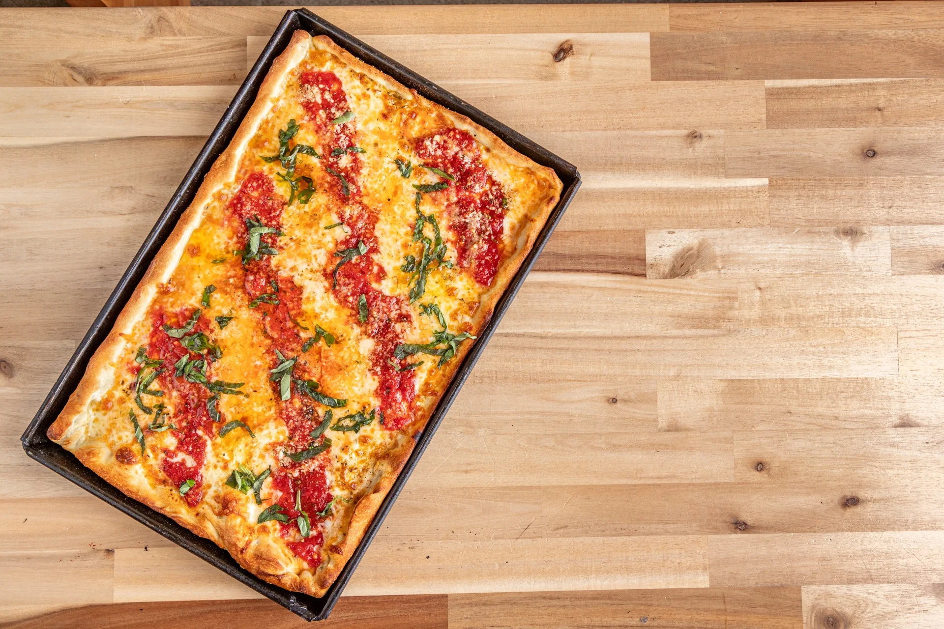 Freshly baked Sicilian pizza with tomato sauce and basil