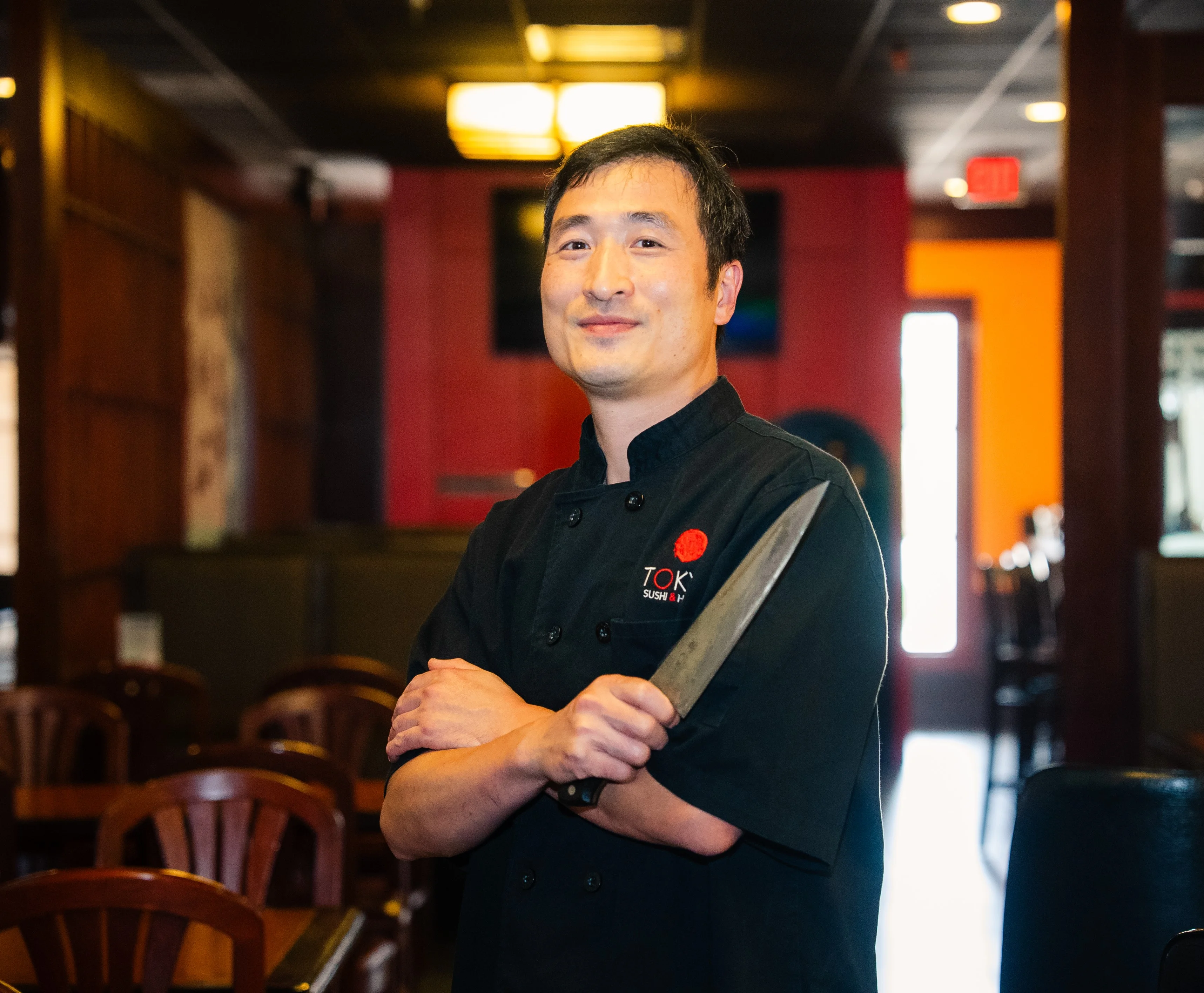 Chef holding a knife in a sushi restaurant interior