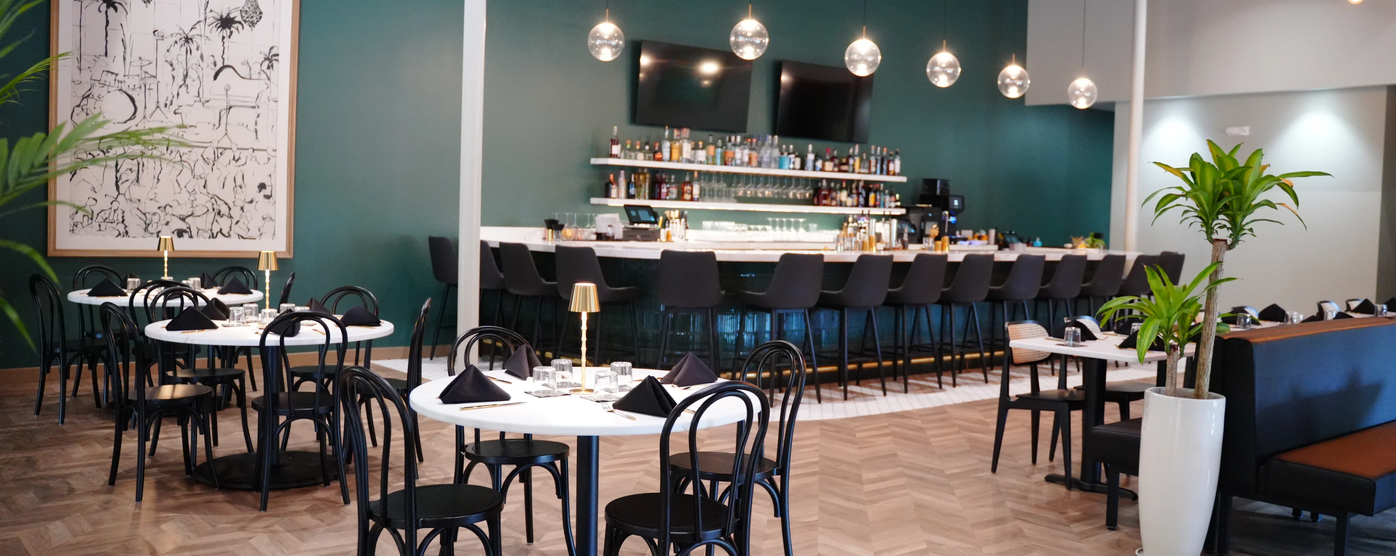 Round dining tables with thonet-style chairs in front of curved large bar