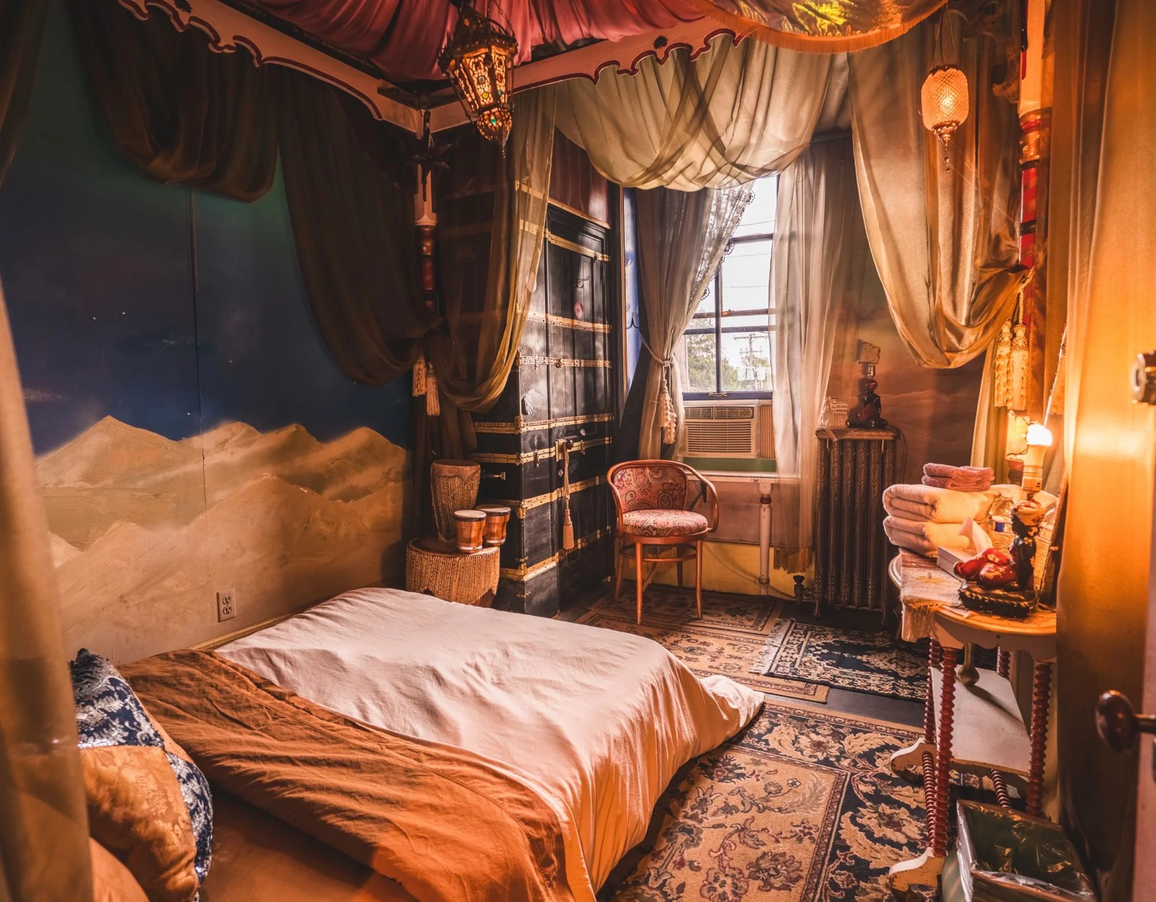 Cozy, decorated bedroom with warm tones and artistic wall mural.