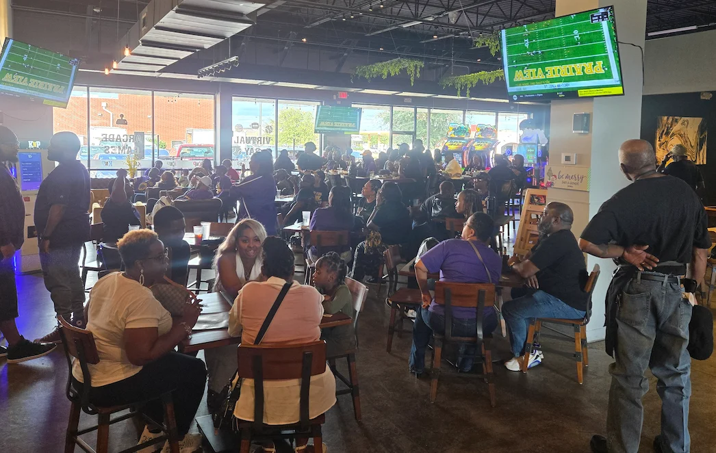 Busy restaurant interior with patrons enjoying food and watching sports.