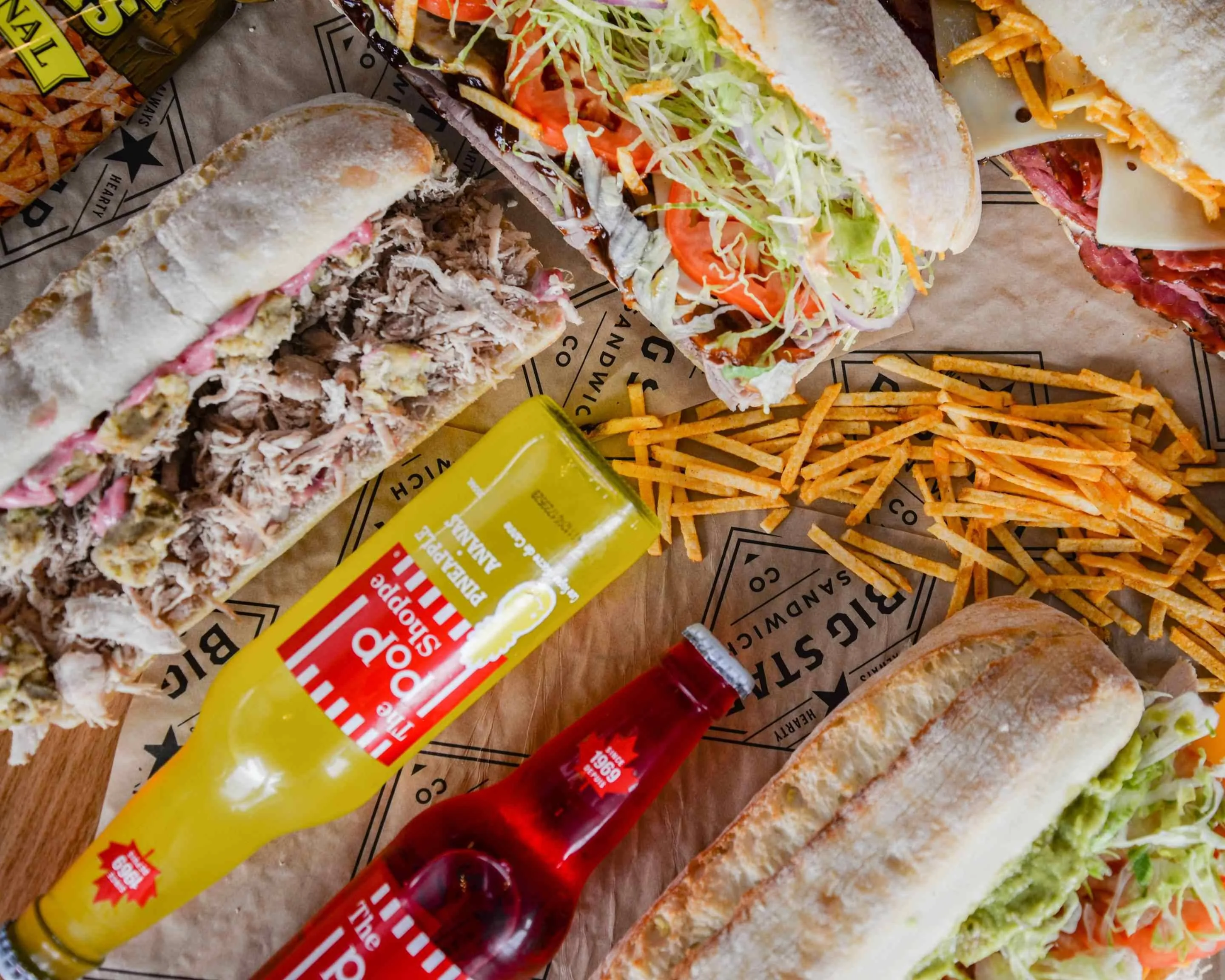 Assorted sandwiches with fries and drinks on a rustic table
