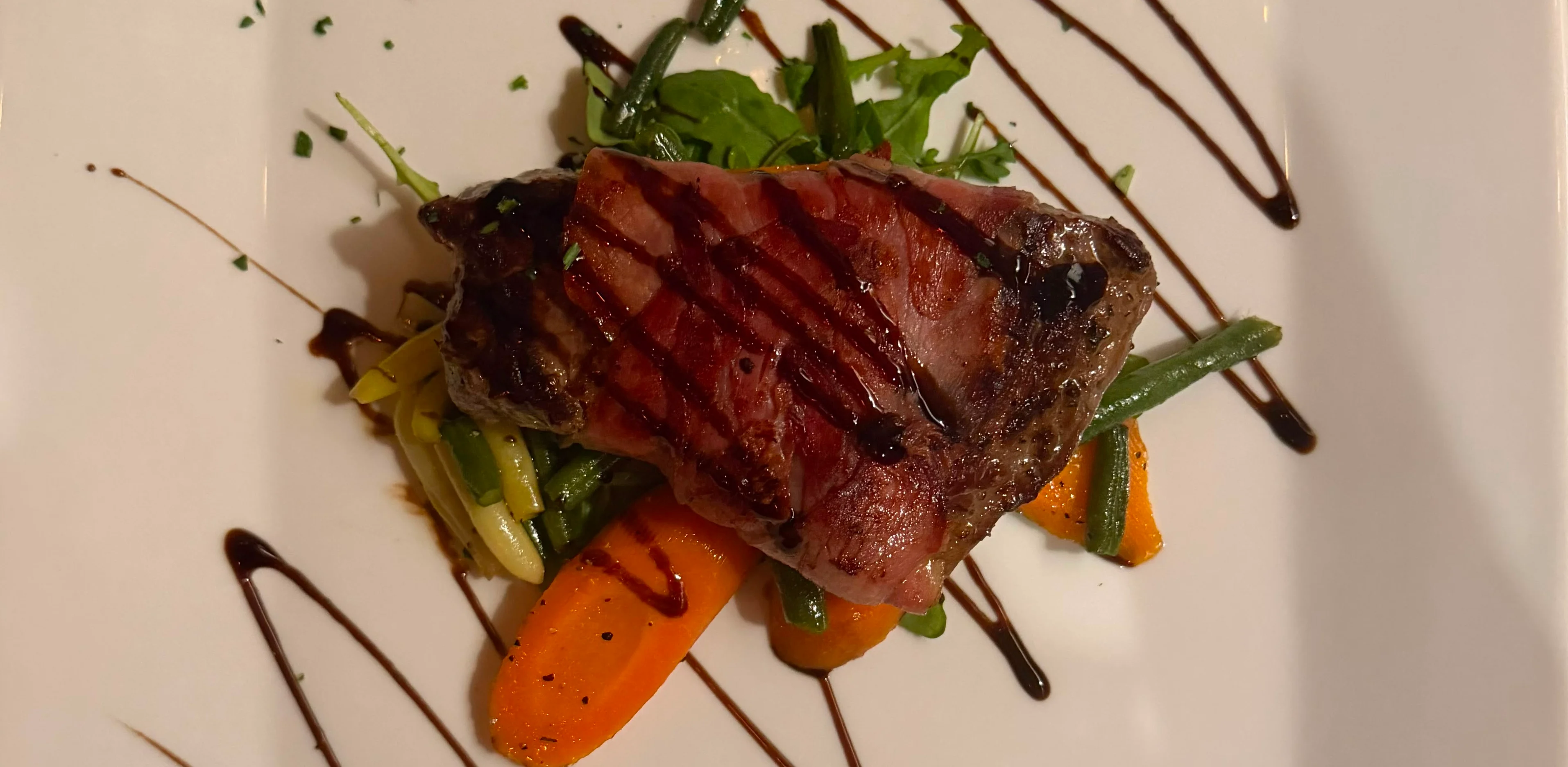 Plated grilled steak with vegetables and balsamic glaze
