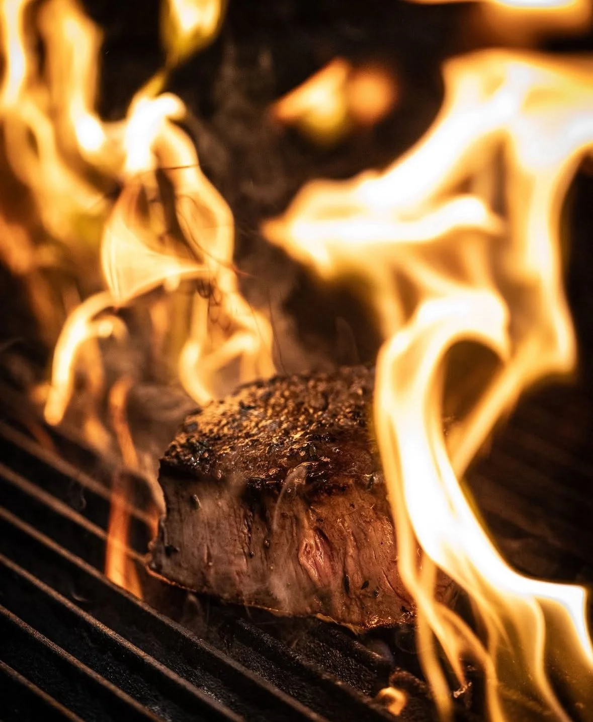 Grilled steak with flames in a barbecue setting
