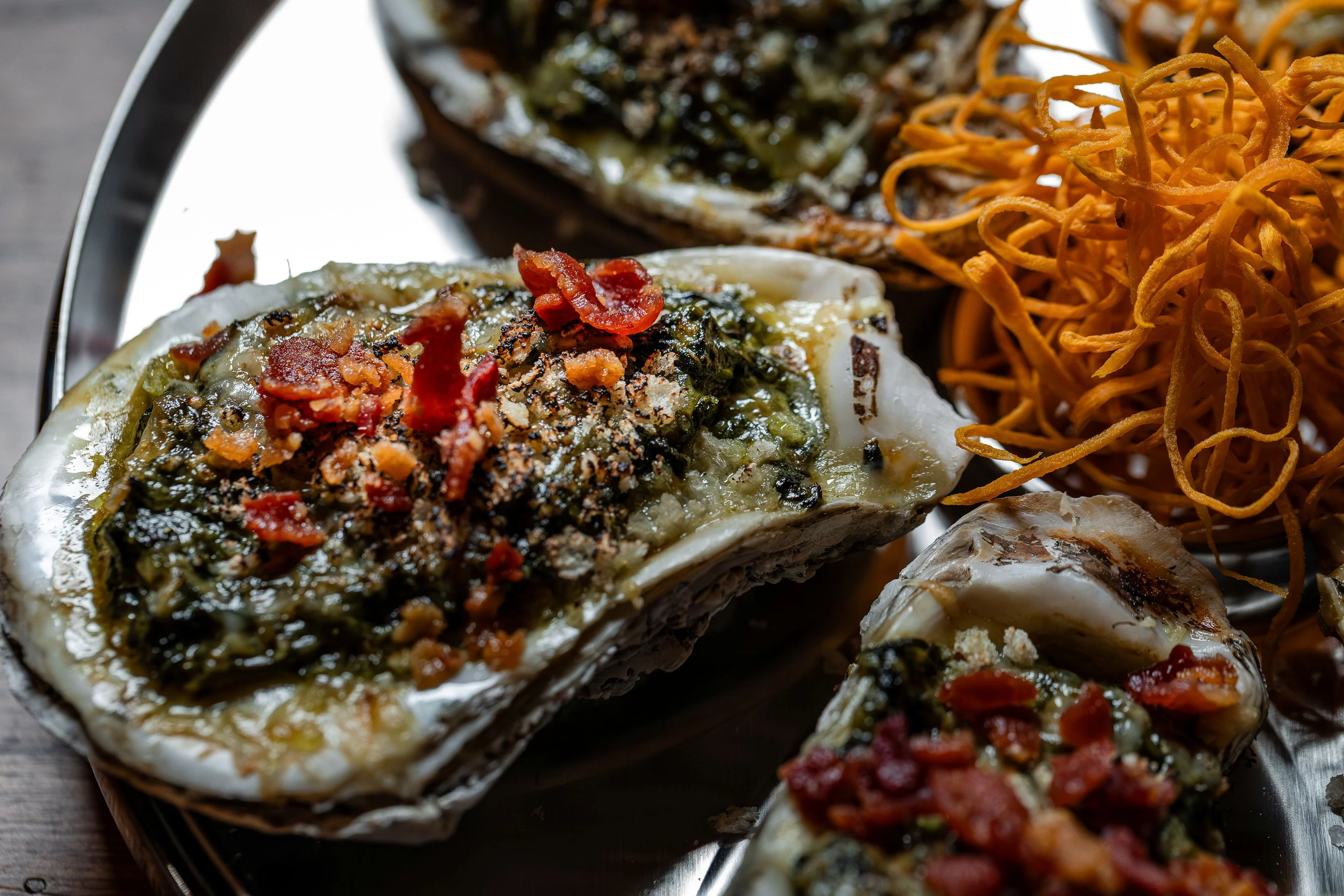 Baked oysters Rockefeller topped with herbs and crispy bacon