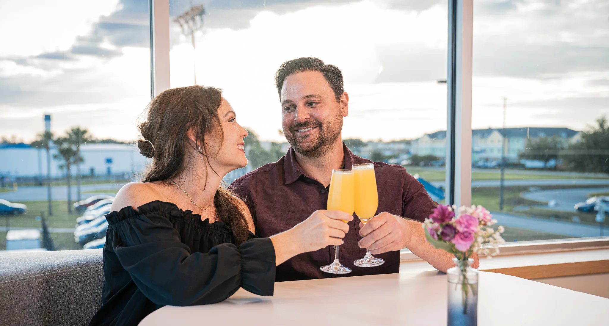 Couple toasting with mimosas in a bright restaurant setting