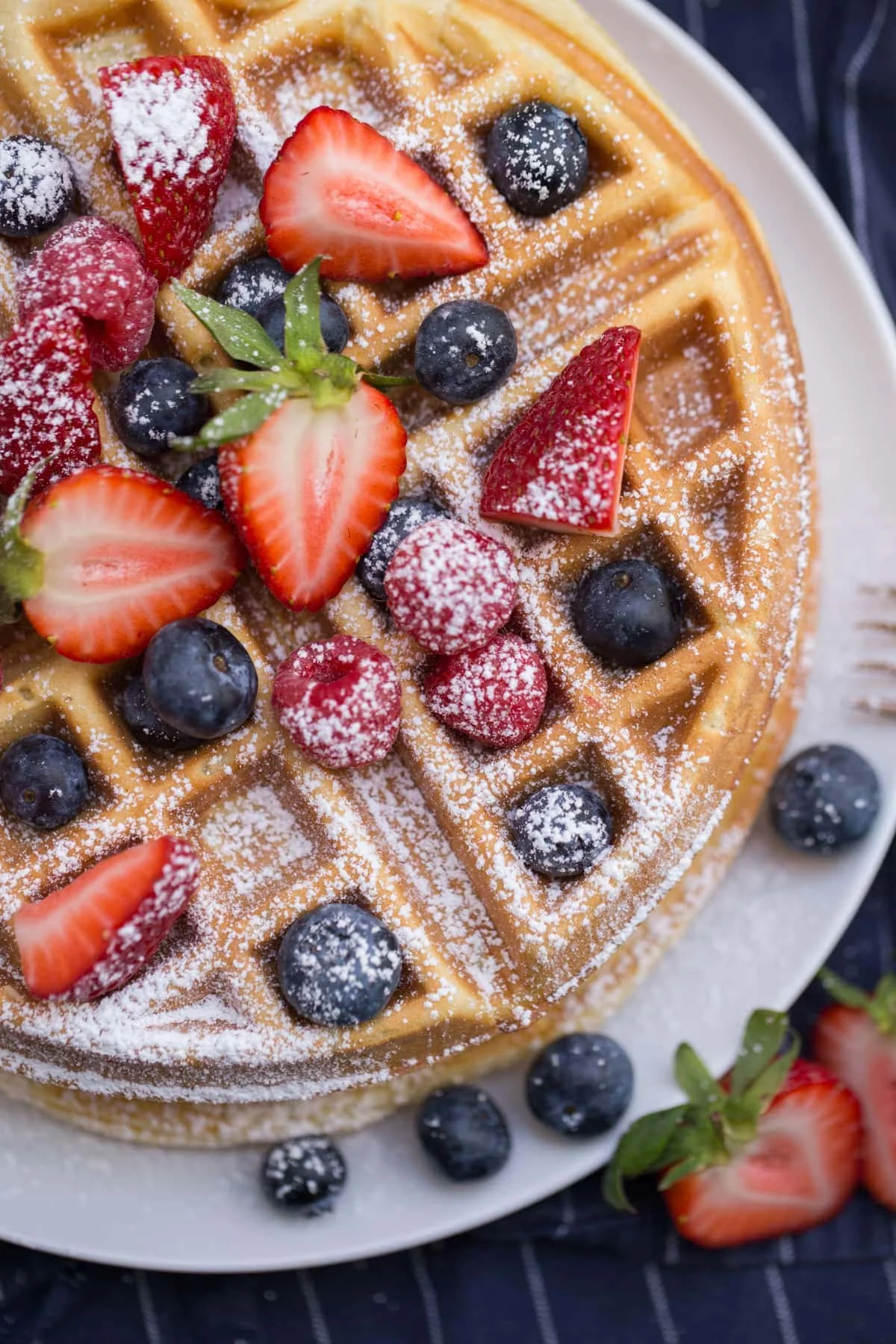 Belgian waffle topped with fresh berries and powdered sugar