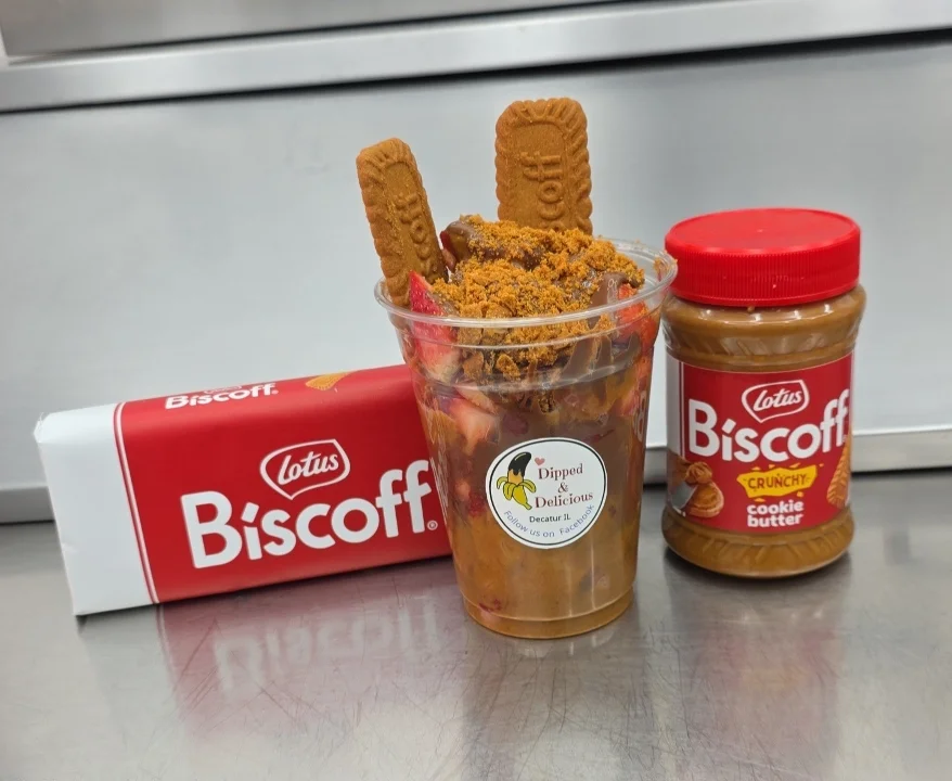 A dessert cup filled with cookie butter, topped with crushed cookies and fruit, alongside a jar of cookie butter.