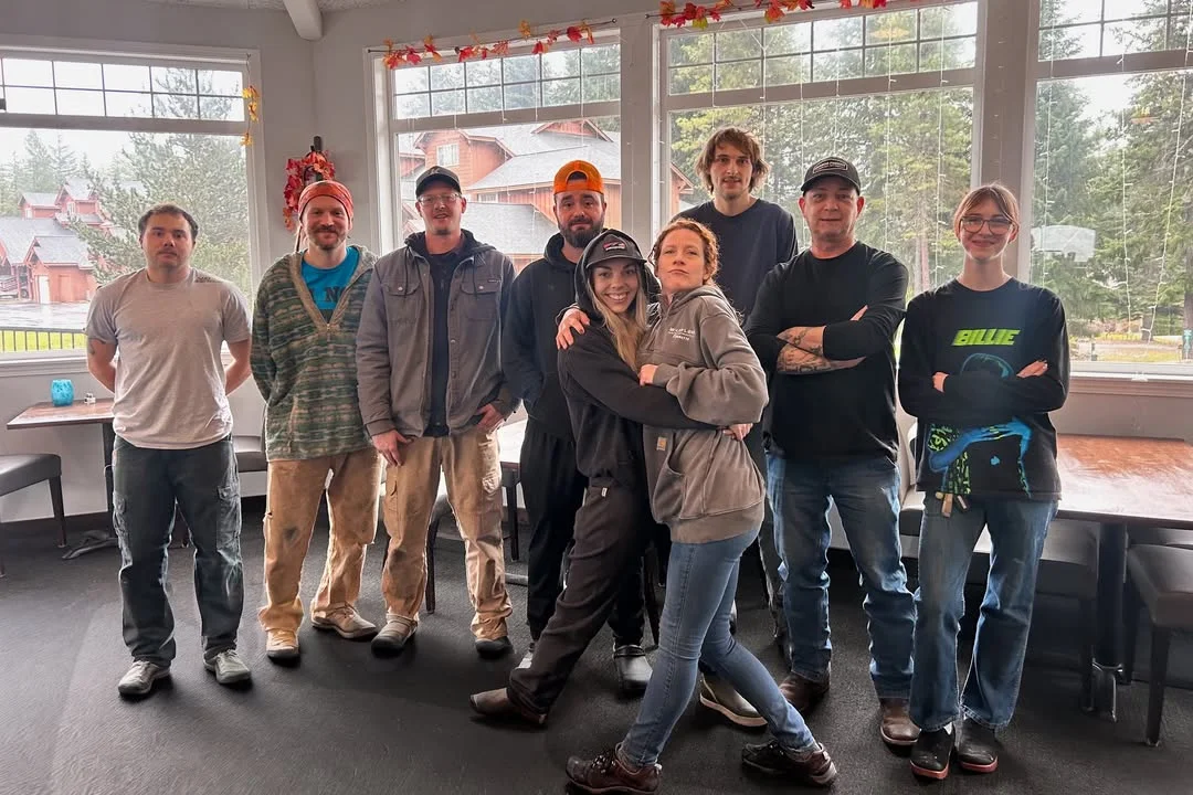 A group of people posing together indoors, smiling and dressed casually.