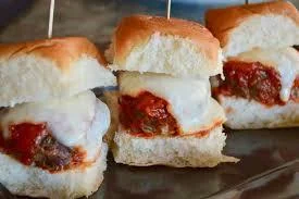 Three mini meatball sandwiches, each served on a soft bun and topped with marinara sauce and cheese.