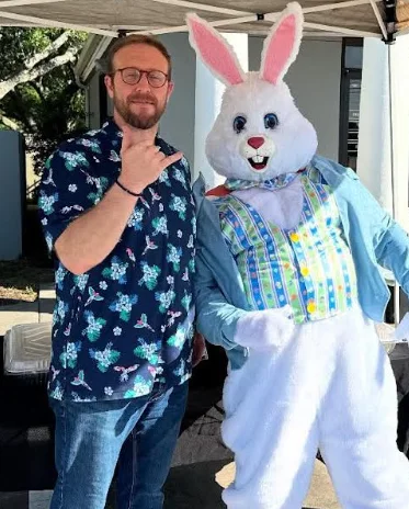 Person posing with Easter Bunny mascot at an outdoor event