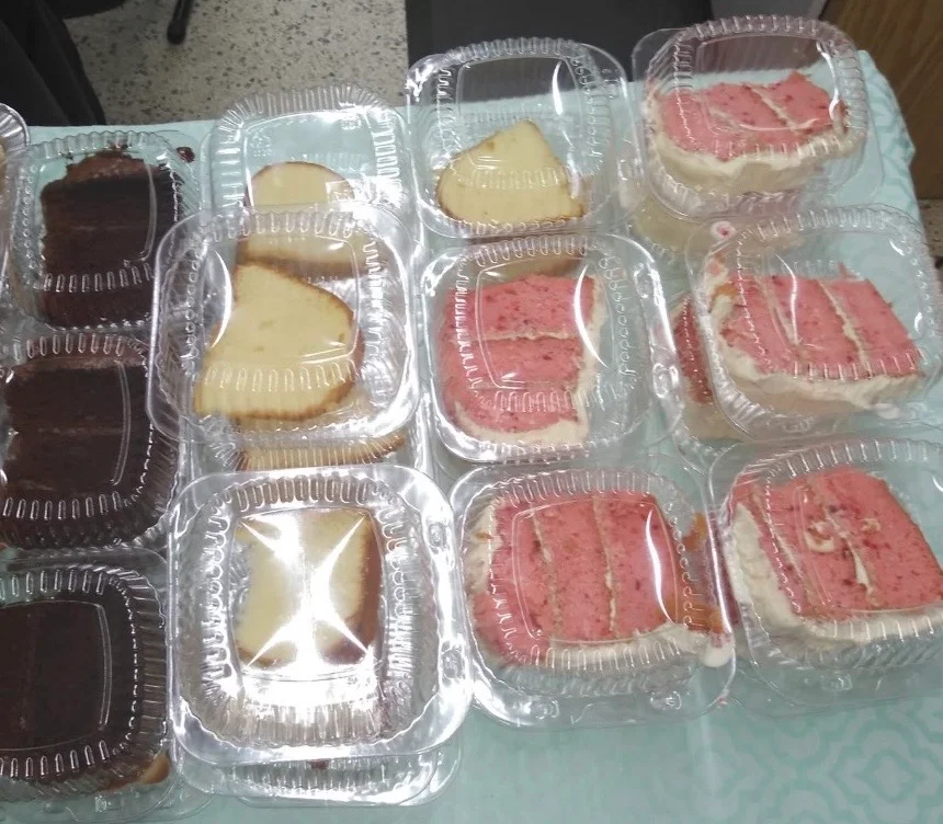 Various slices of cake in clear plastic containers, including chocolate and strawberry flavors.