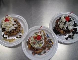 Decadent funnel cakes topped with whipped cream and cherries