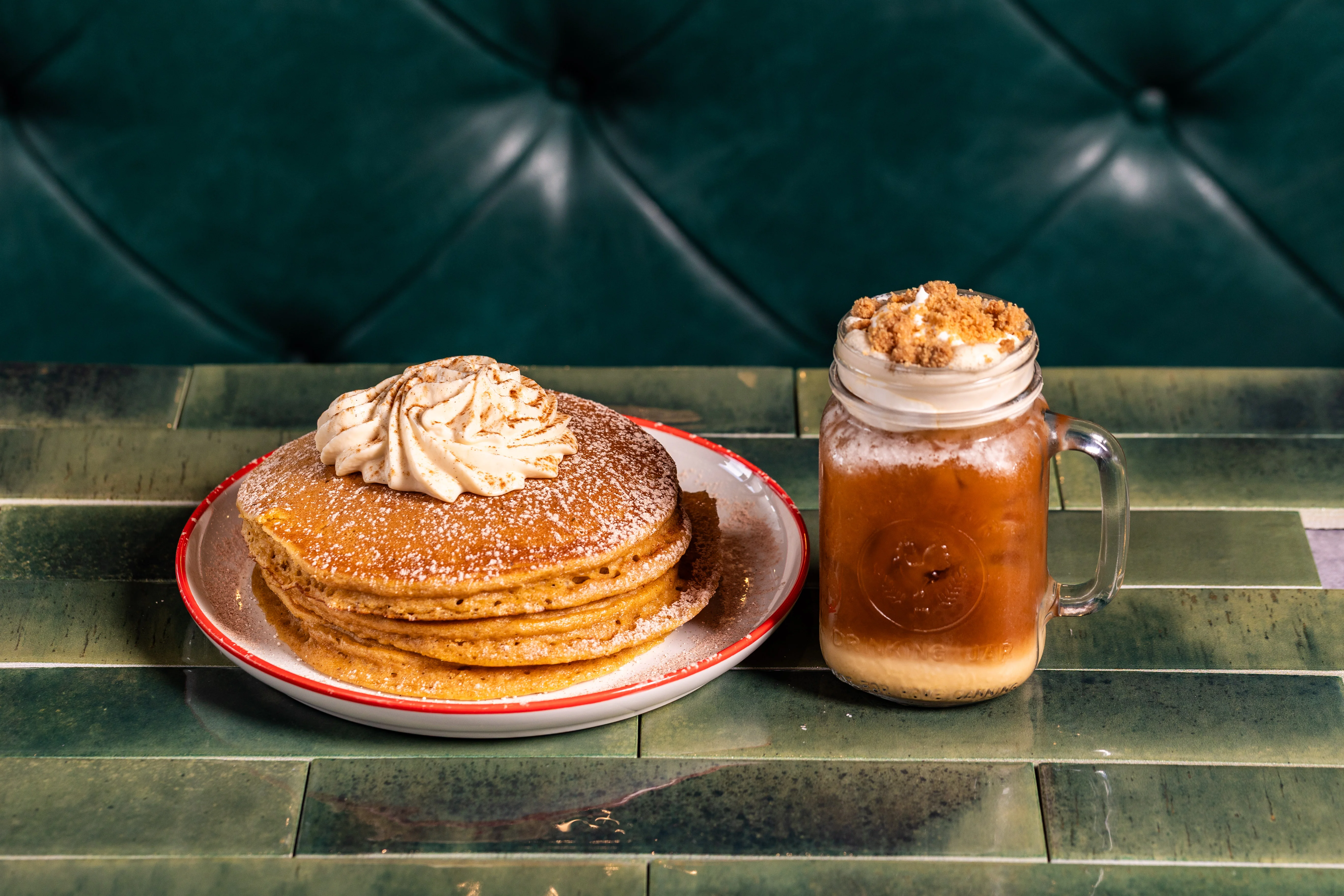 Fluffy buttermilk pancakes with whipped cream and iced coffee in a mason jar