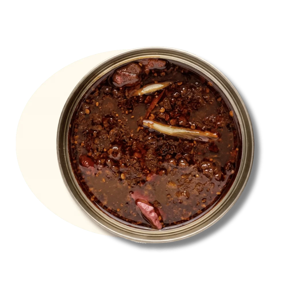 A jar of rich, dark chili oil with spices and herbs visible.