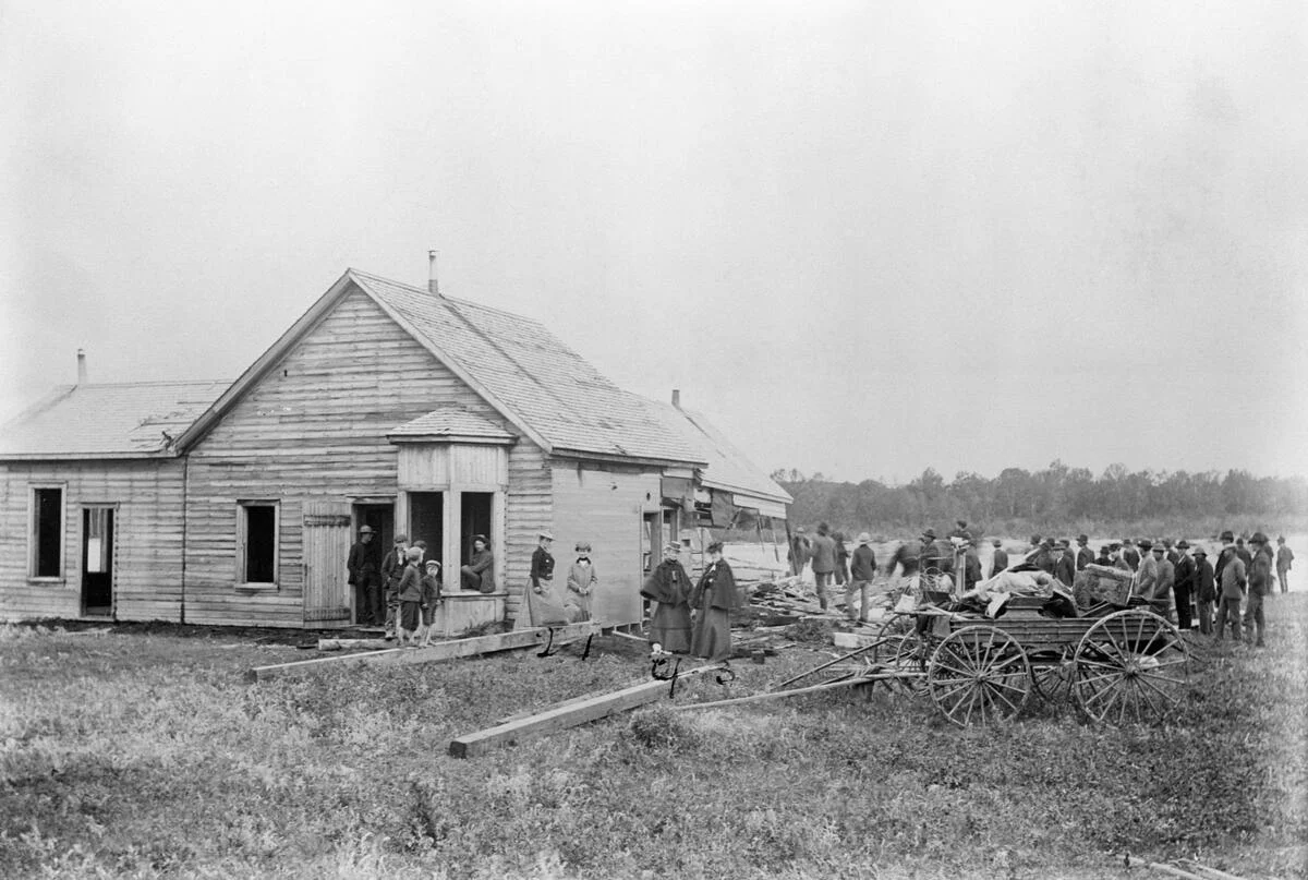 Historic building with people gathered outside in a rural setting
