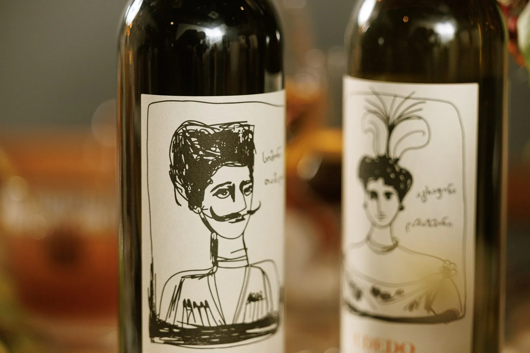 Two Georgian wine bottles with hand-drawn portrait labels