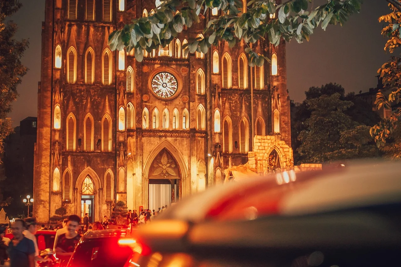 Historic church illuminated at night with bustling street activity in the foreground.