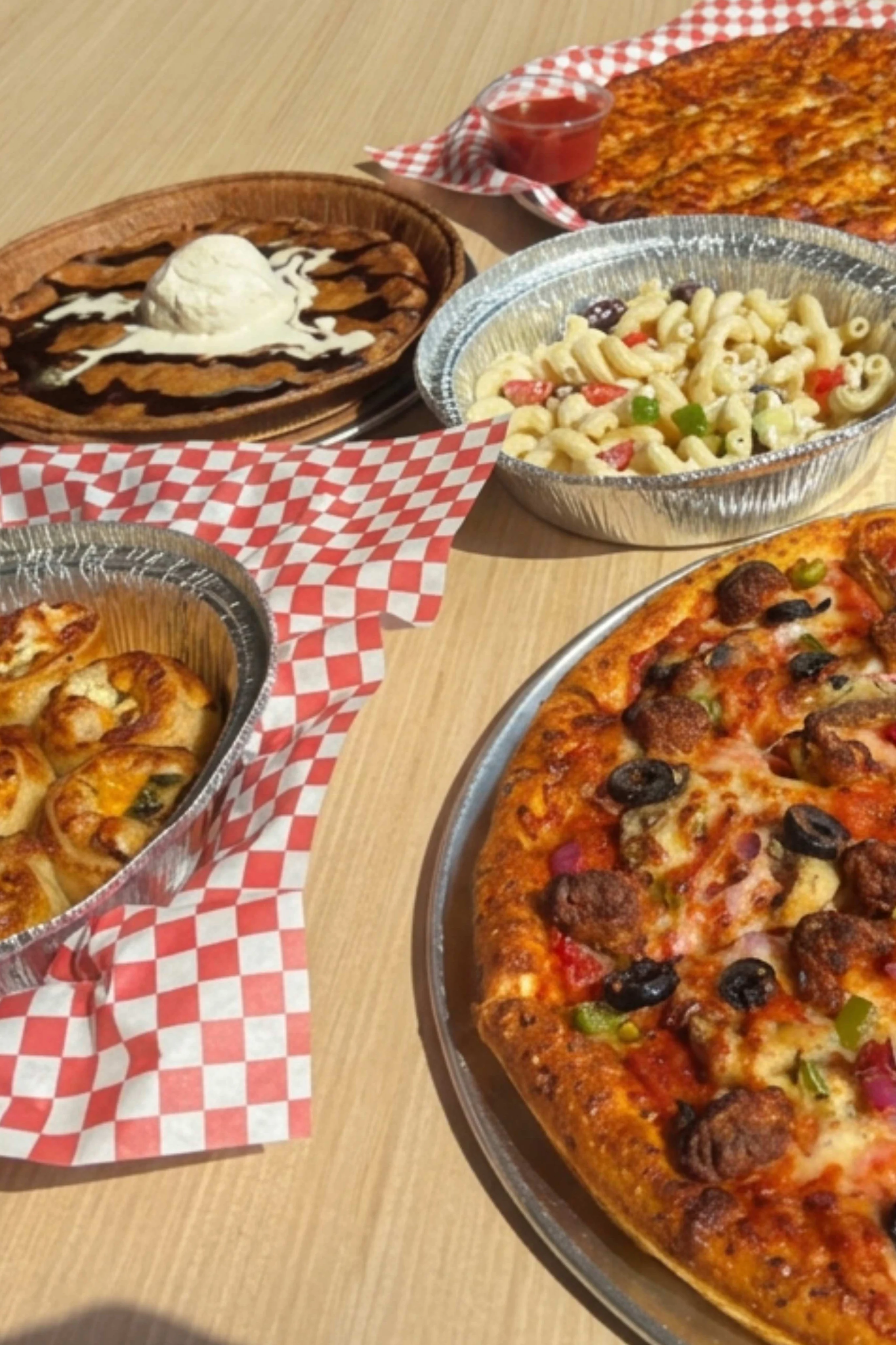 Delicious pepperoni pizza with sides of cheesy rolls and dessert