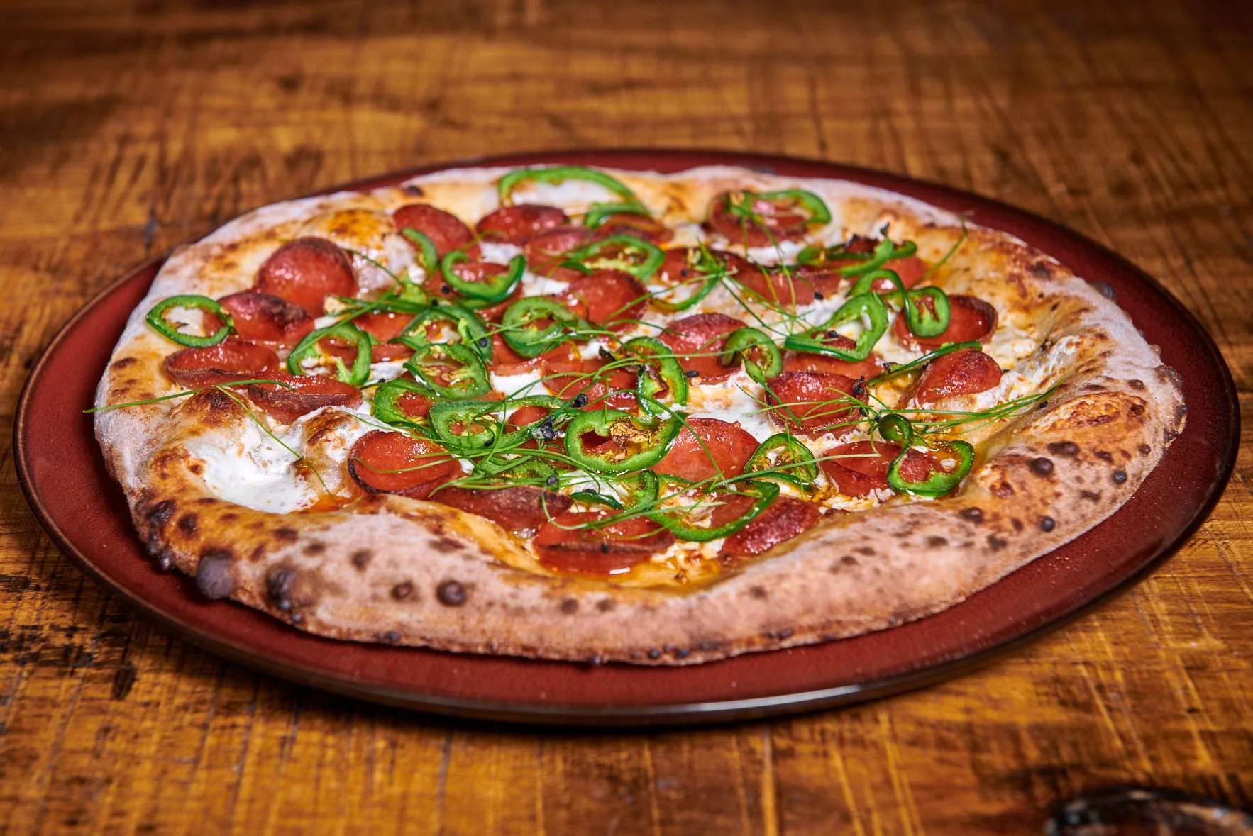 Mount Kisco wood fired pizza topped with bacon jam, pepperoni, jalapeño, cheese, and chives