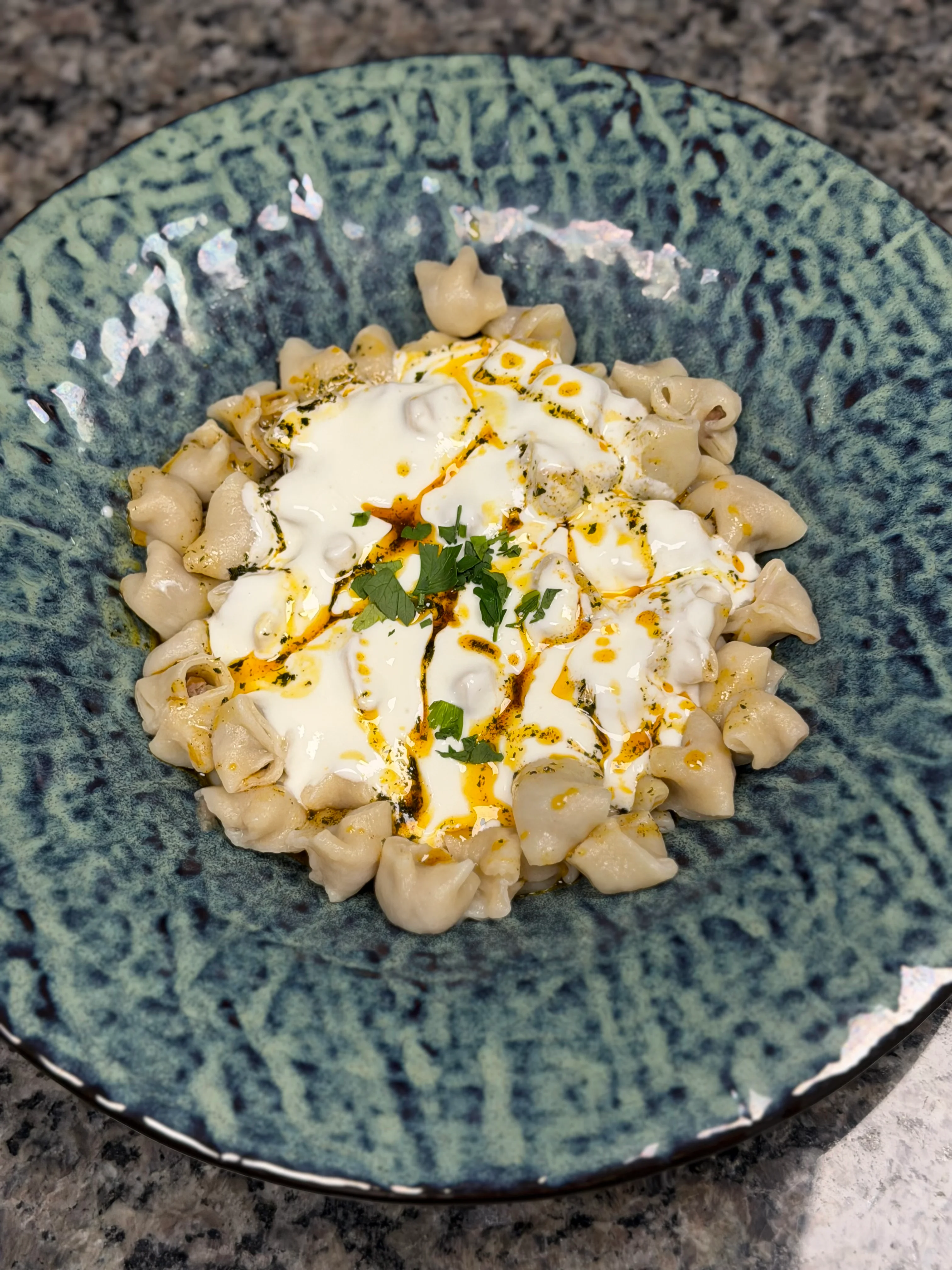 Turkish manti topped with yogurt and spices