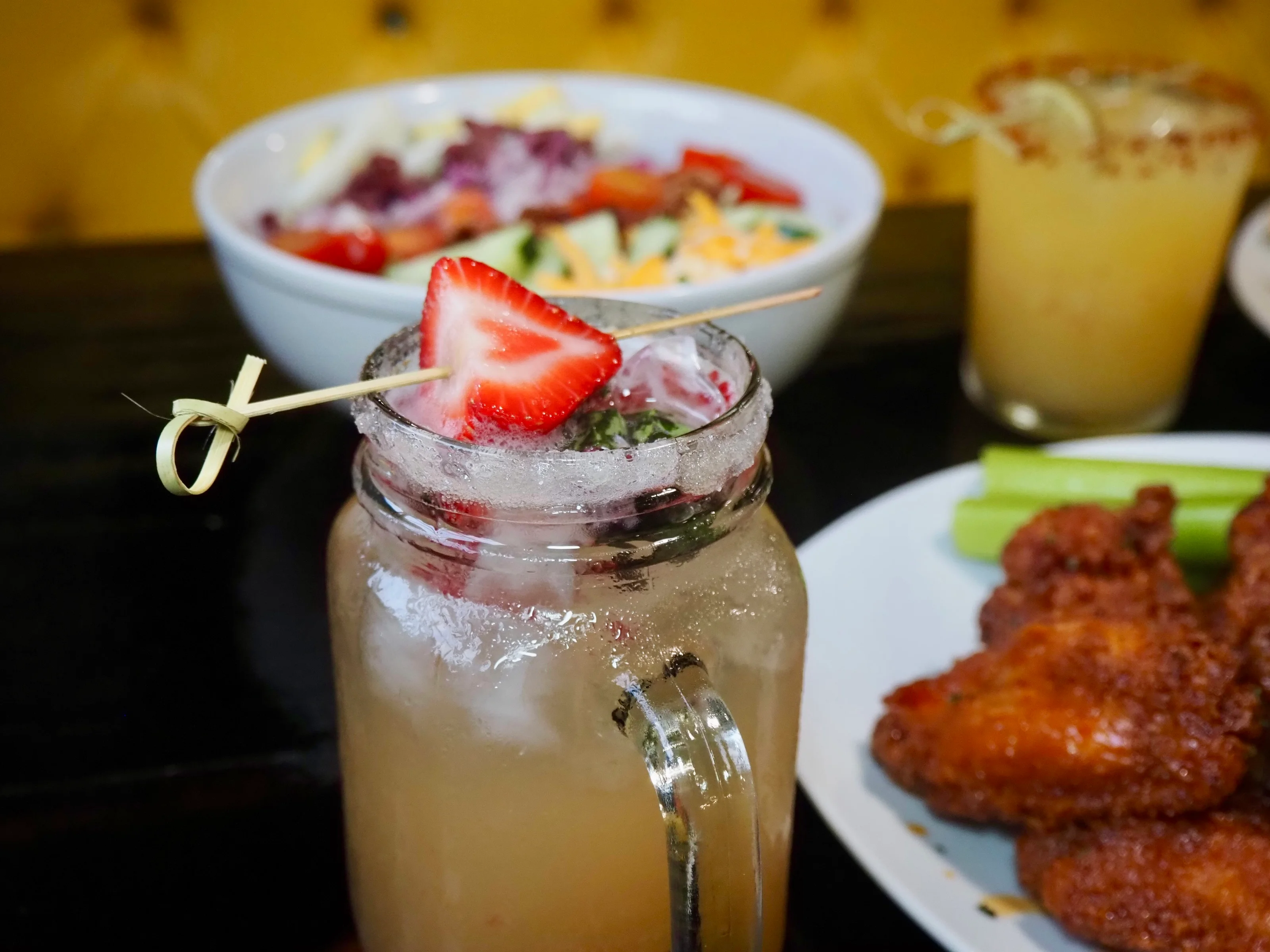 Refreshing cocktail with strawberry garnish in a vibrant bar setting