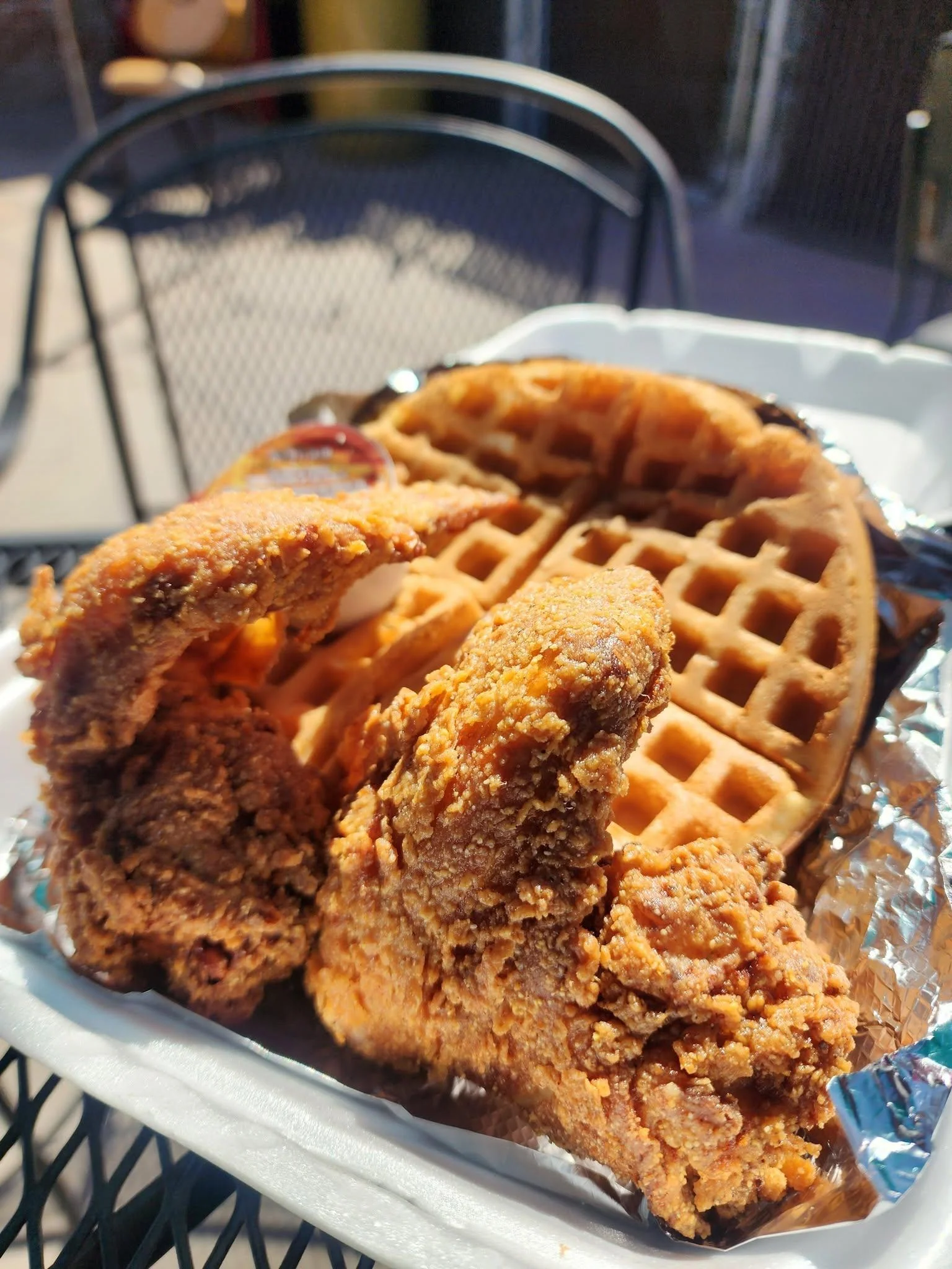 A serving of fried chicken with two waffles, resting on a silver tray.