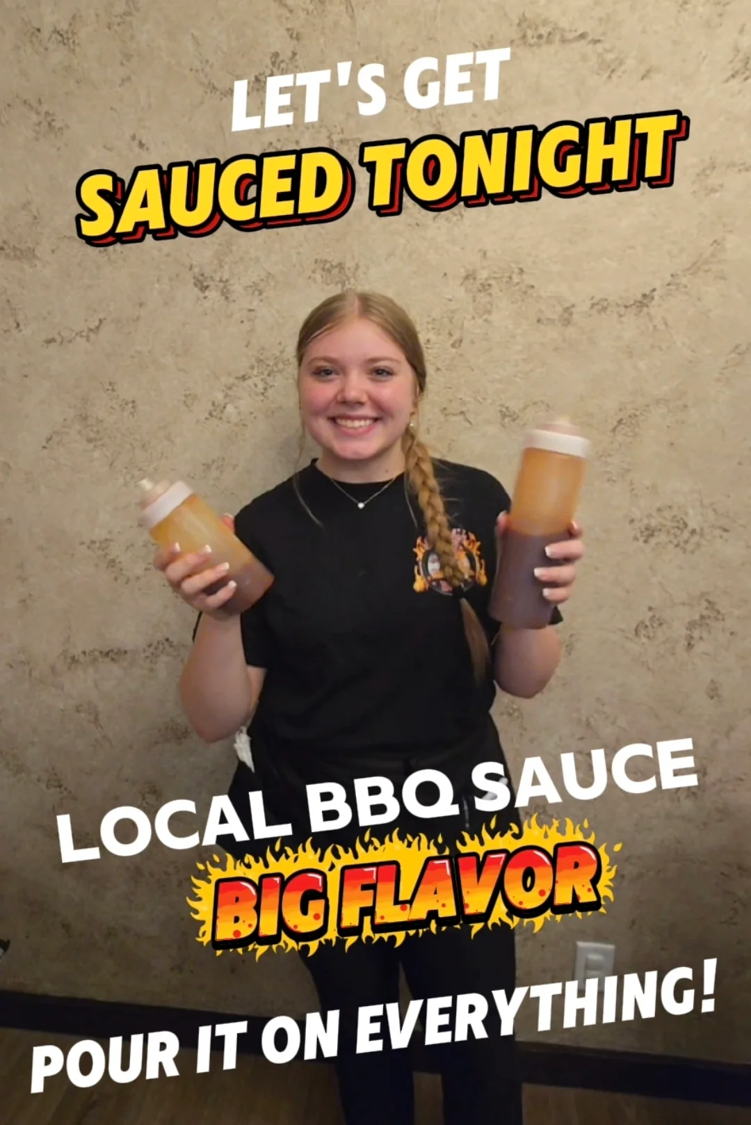 Person holding two bottles of BBQ sauce with promotional text.