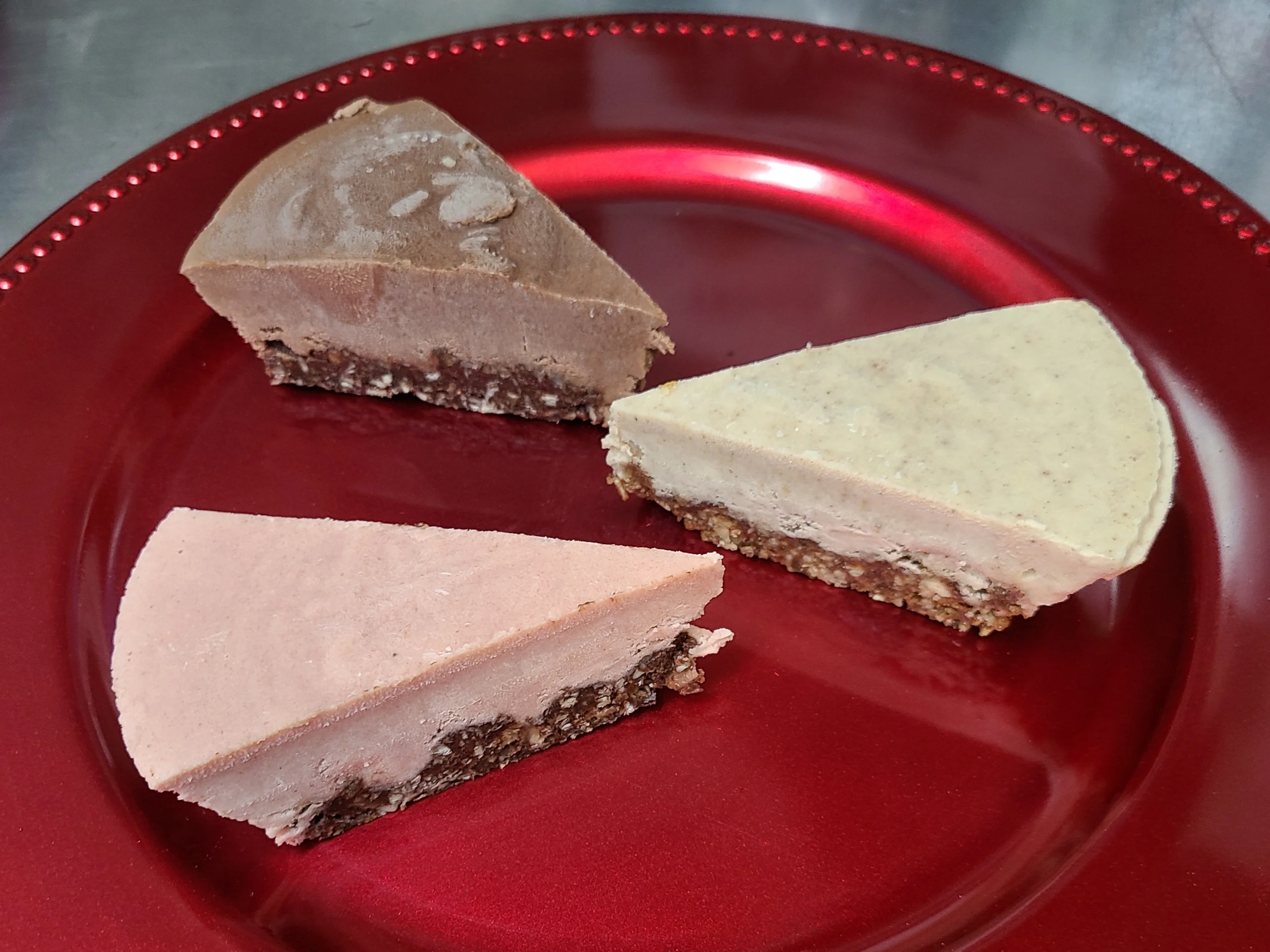 Assorted raw vegan cheesecakes on a red plate