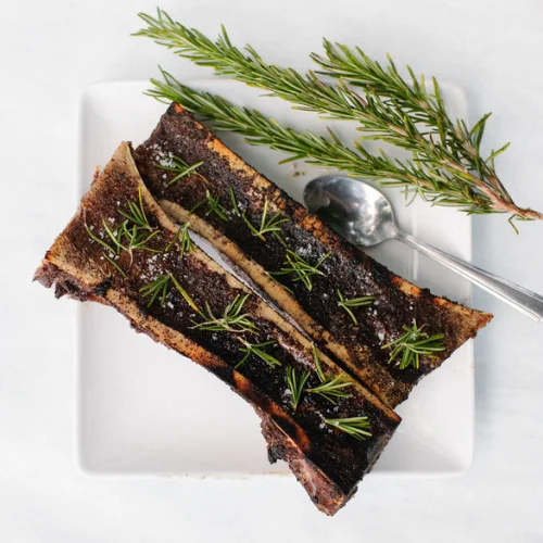 Roasted bone marrow with herbs on a white plate