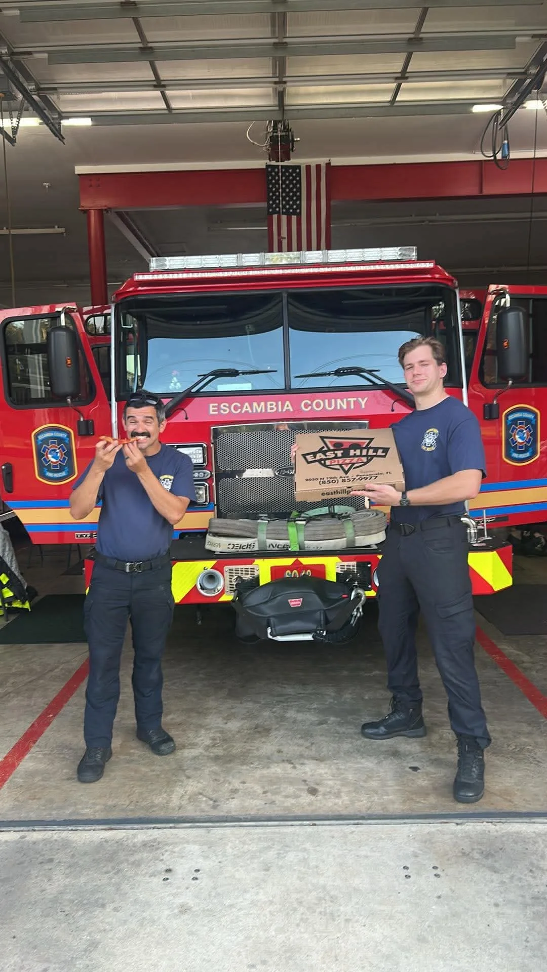 Pizza box delivery to firefighters in front of a red fire truck