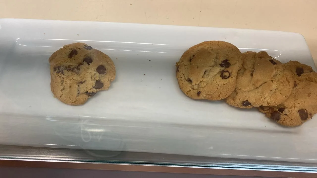 Several chocolate chip cookies arranged on a white serving plate, showcasing their golden-brown color.
