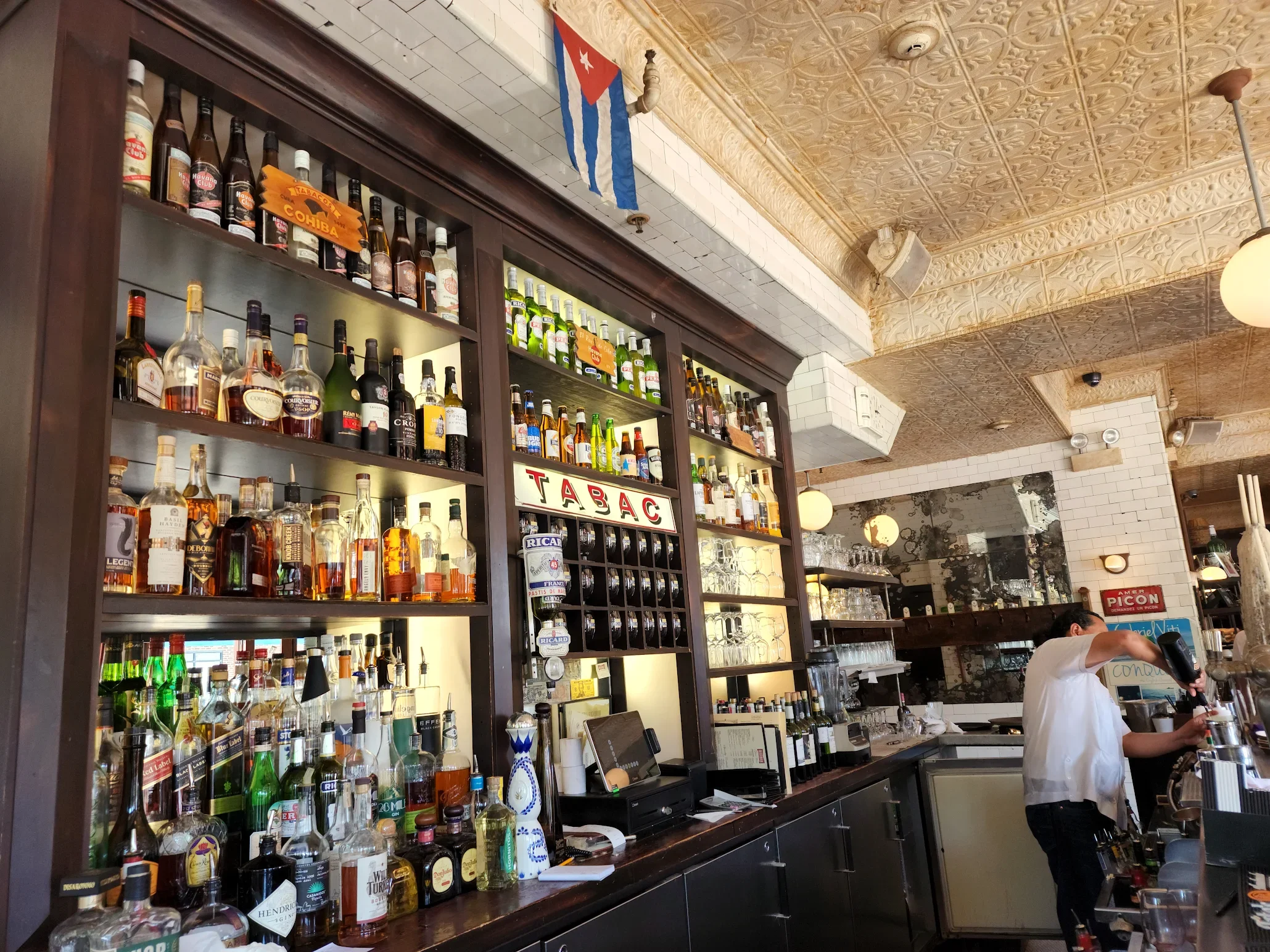Bartender mixing cocktails at a stylish bar with a diverse liquor selection