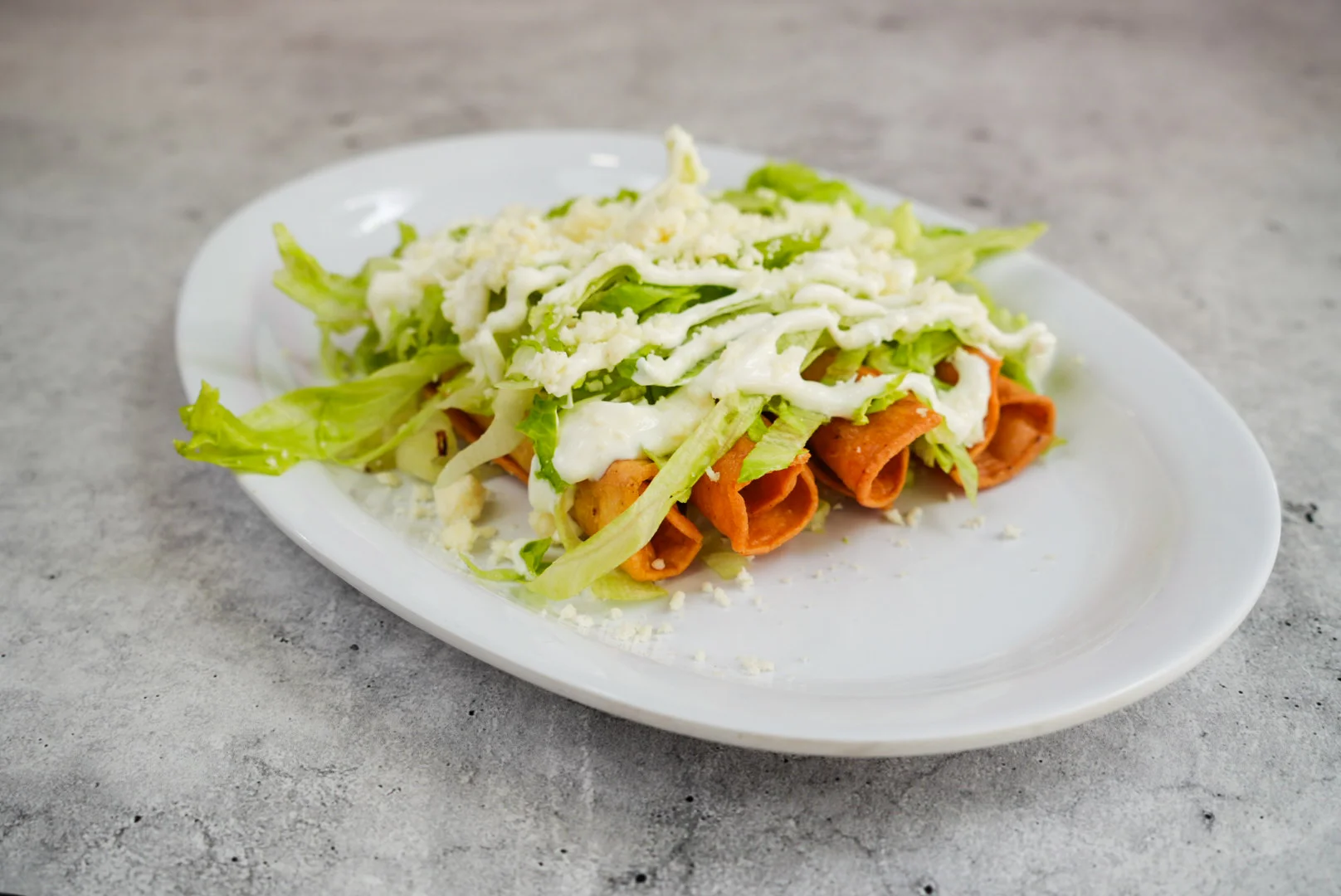 Crispy Mexican flautas topped with lettuce and cream