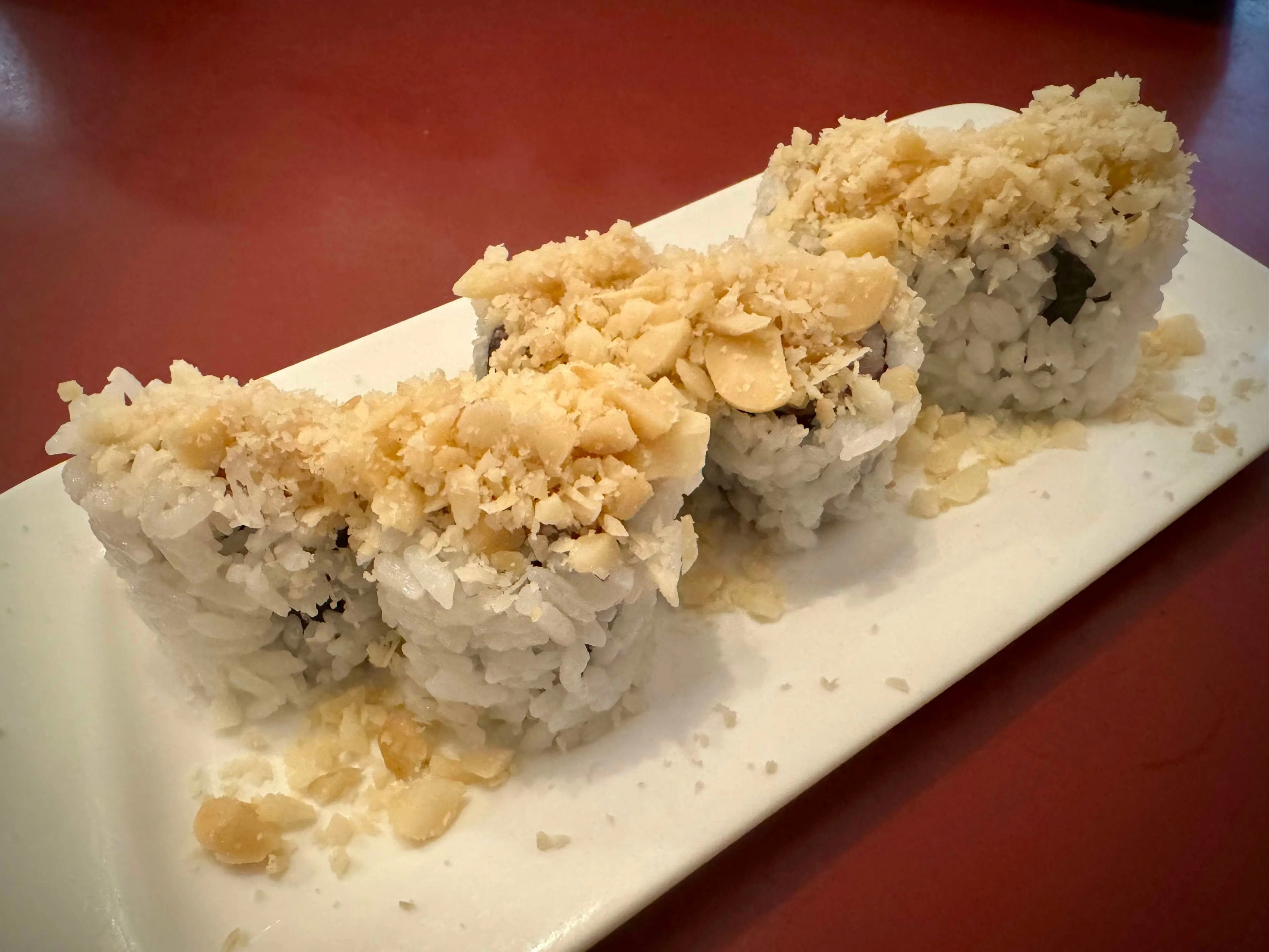 Japanese sushi rolls topped with crunchy flakes on a white plate