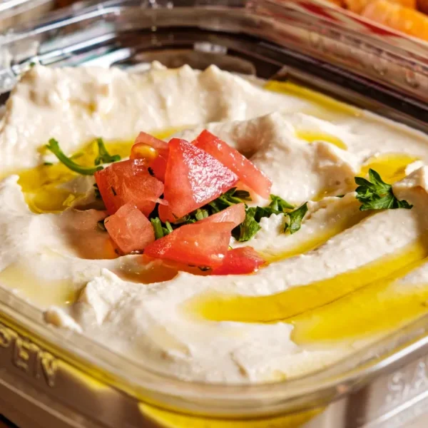 A flavorful sandwich filled with grilled meat, topped with a creamy sauce and fresh herbs, served in a toasted bun.