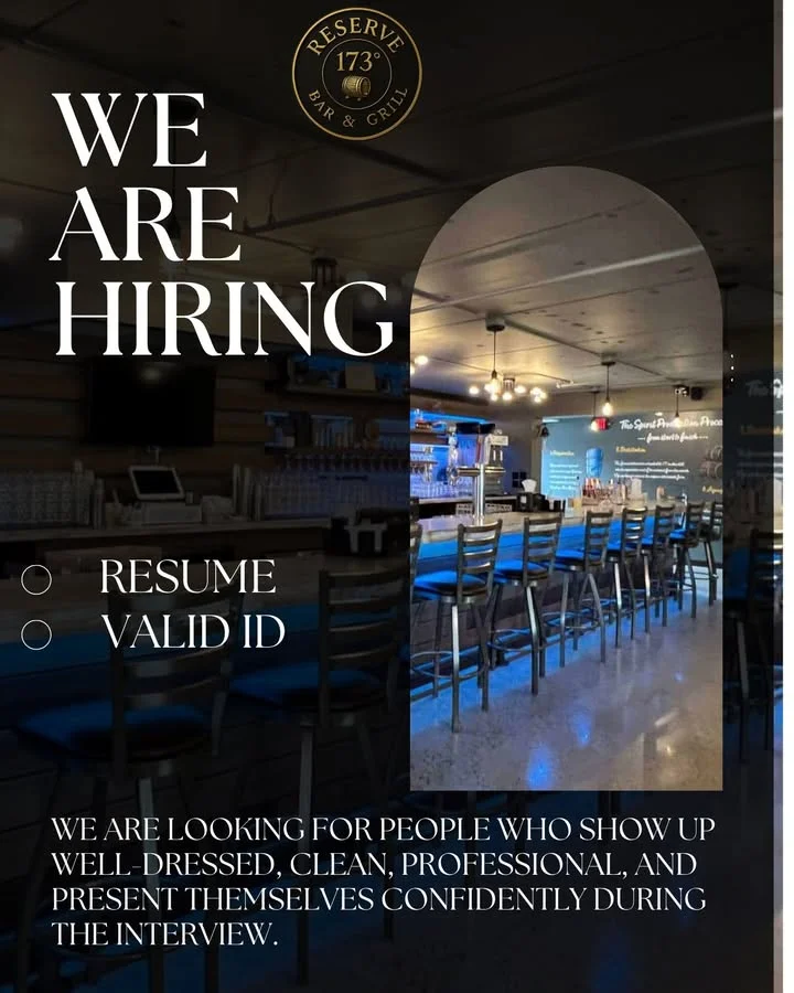A bar and grill establishment with a hiring announcement. The interior features a bar area with stools and a well-lit ambiance.