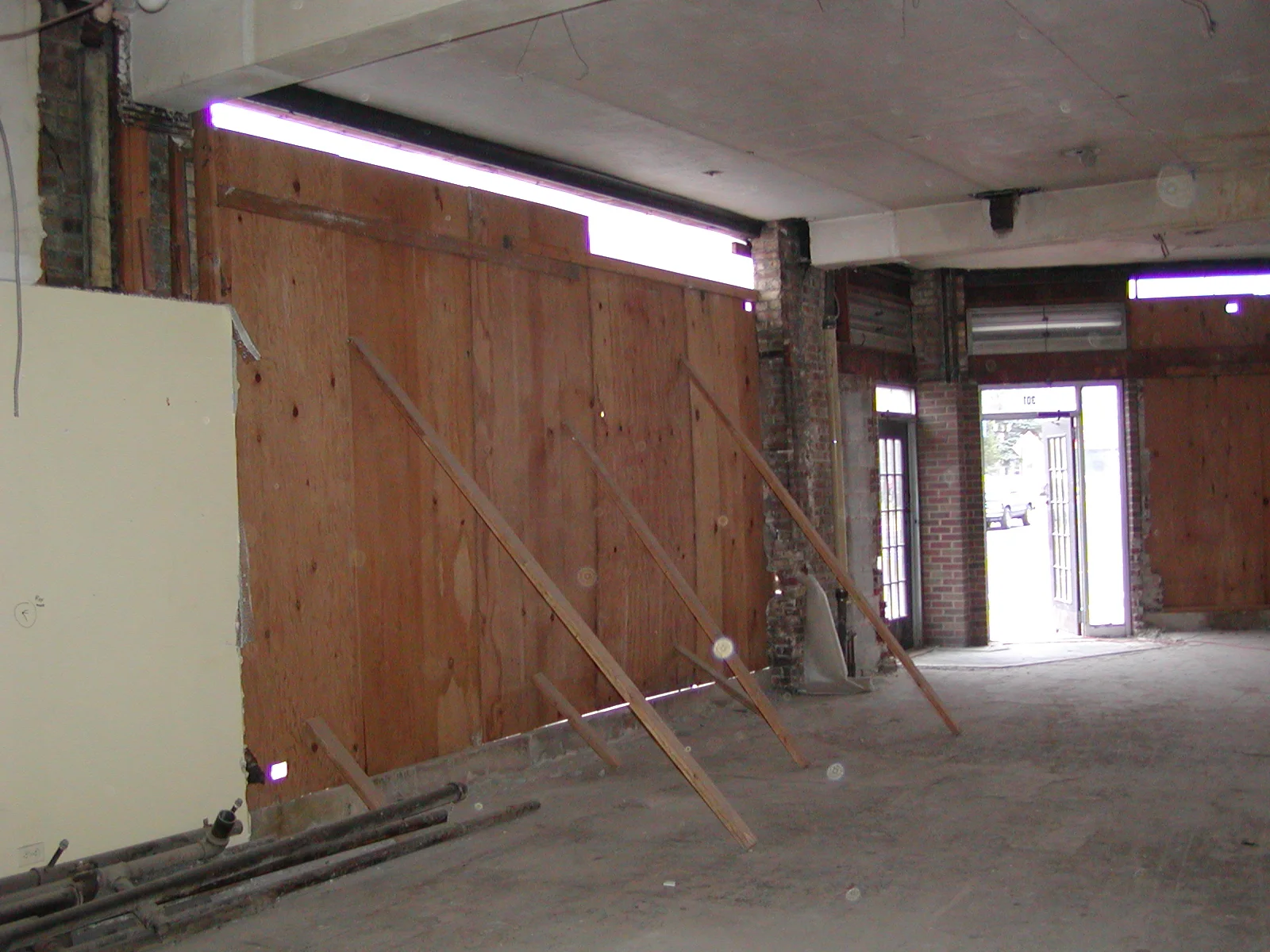 Empty restaurant space under renovation with wooden boards and exposed brick