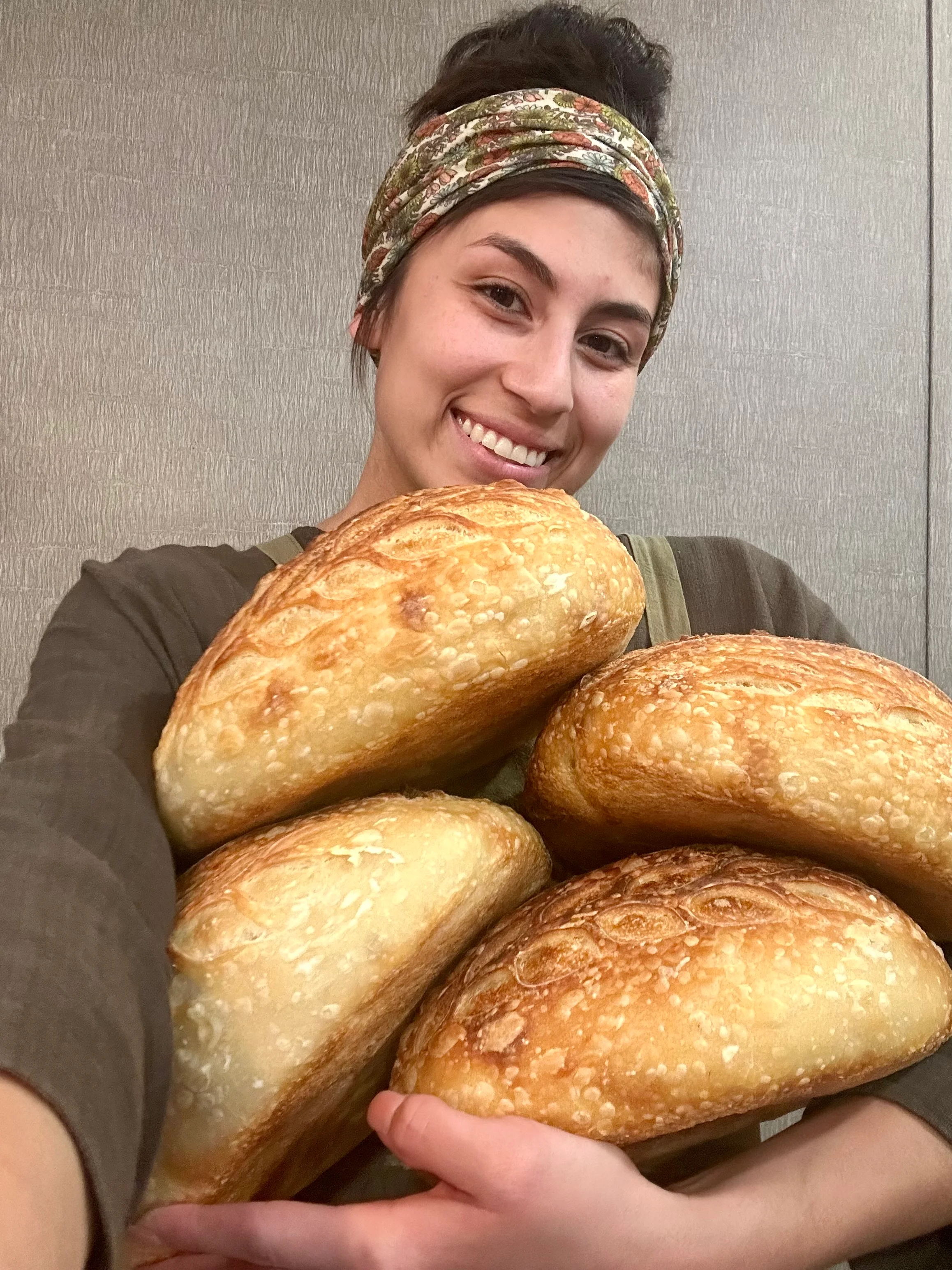 Freshly baked artisan bread loaves held by a smiling baker