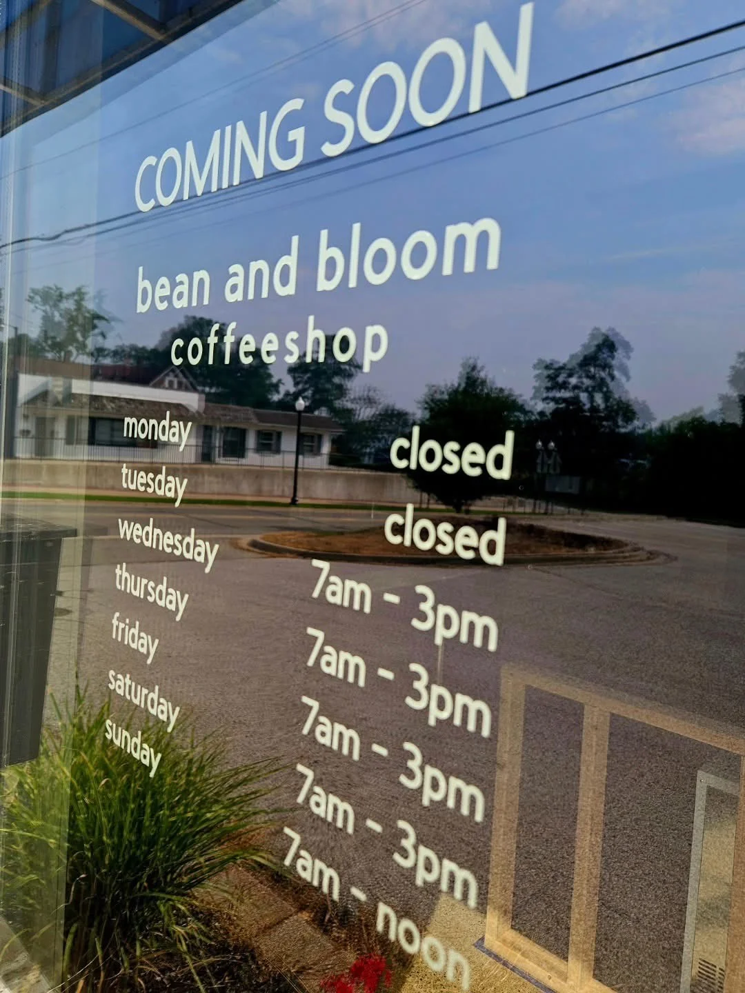 Sign for Bean and Bloom coffee shop with operating hours