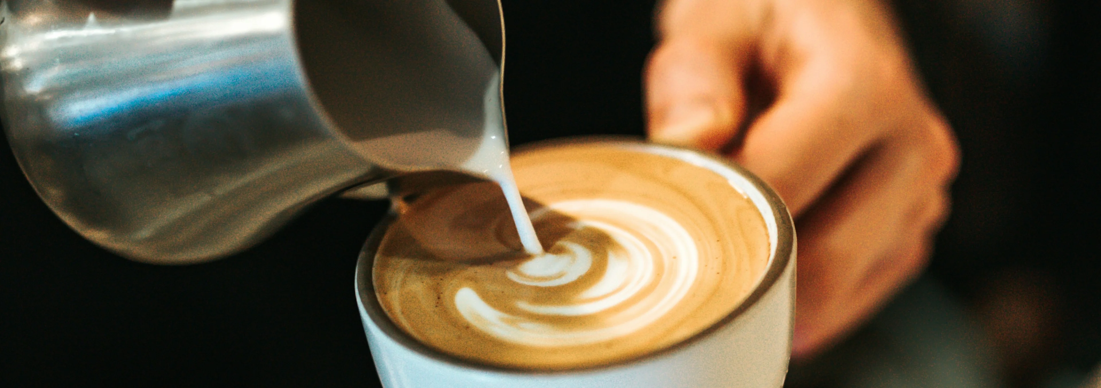 Barista pouring latte art into a cup of coffee
