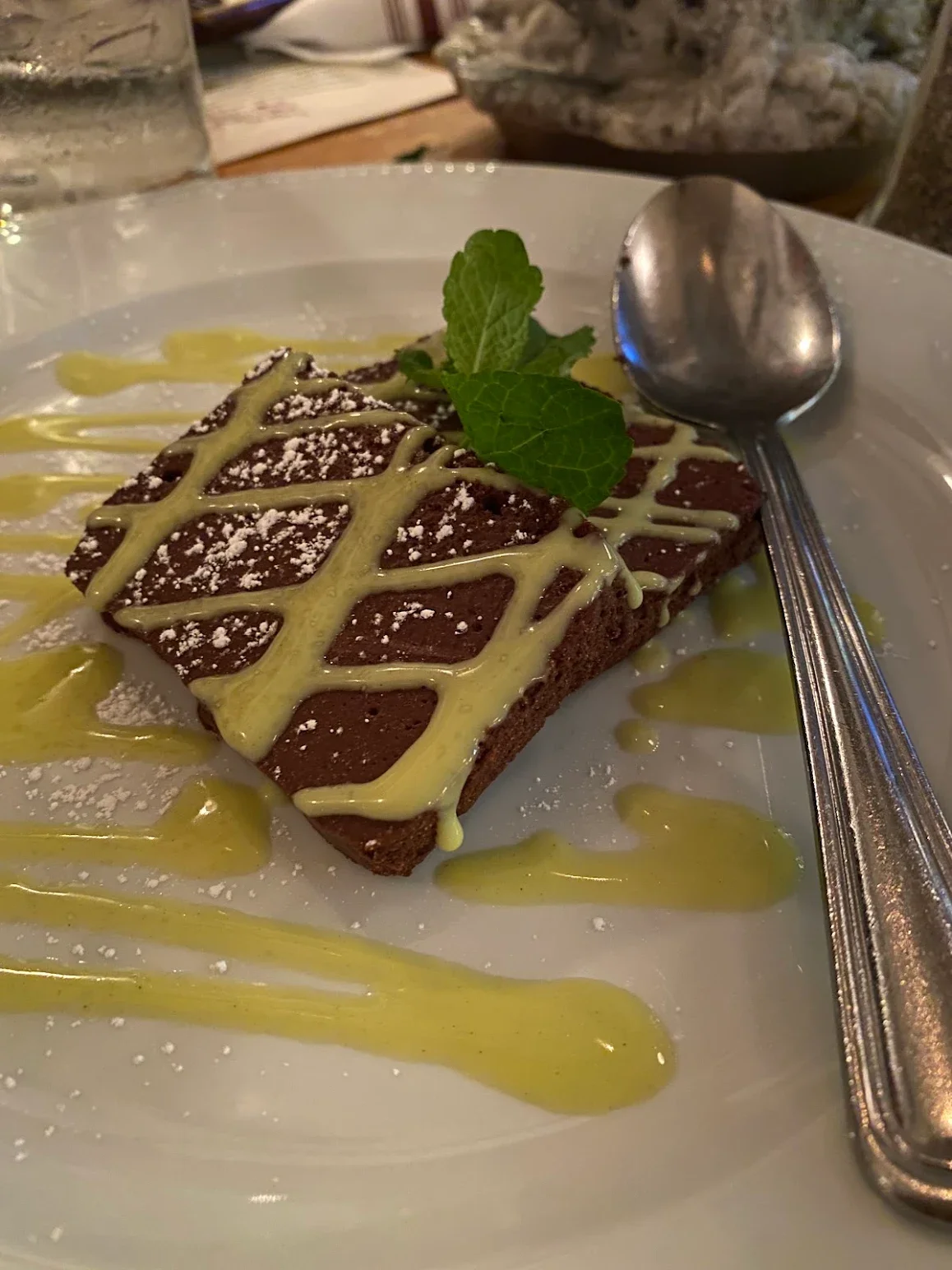 Decadent chocolate brownie with mint garnish and vibrant sauce drizzle