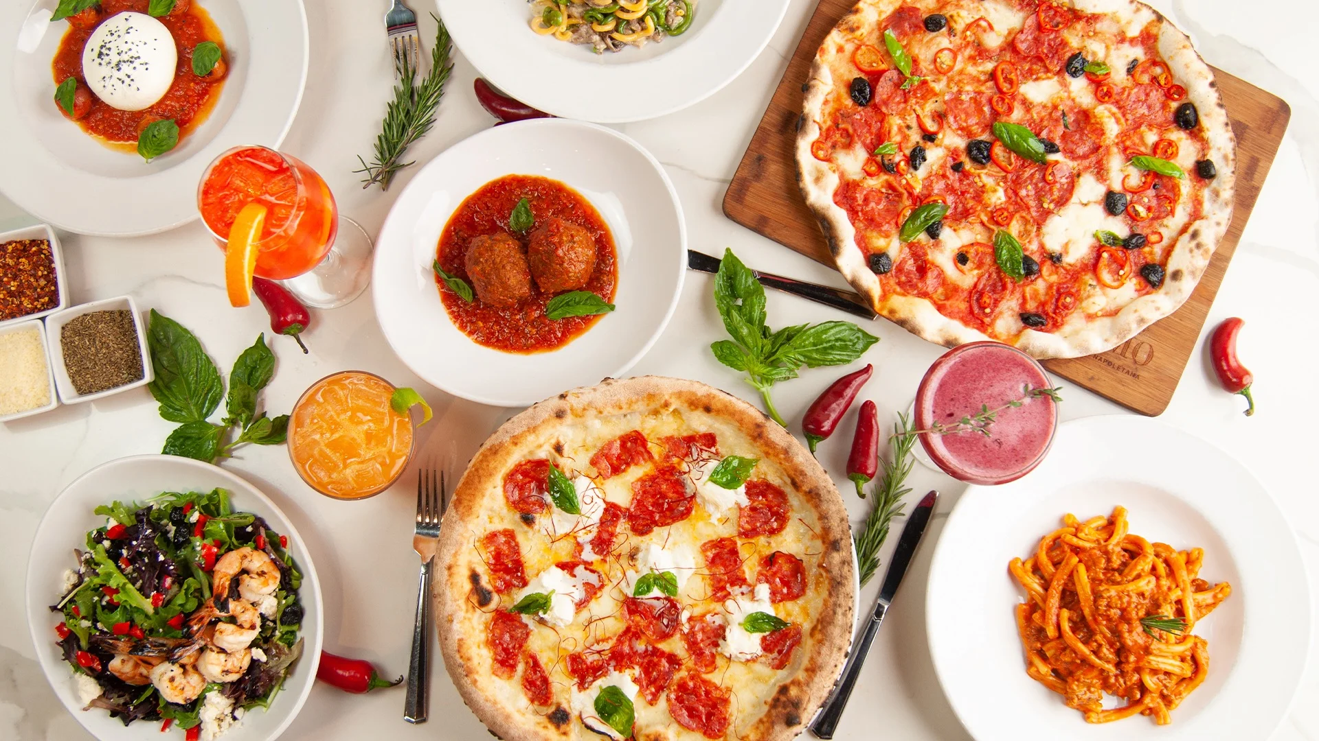 Italian feast featuring pizza, pasta, and shrimp salad on a dining table